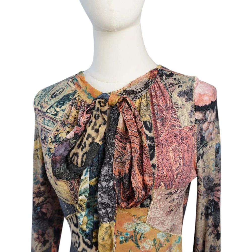 Dettaglio ravvicinato dello scollo arricciato con colletto lavallière annodato a fiocco del vestito Roberto Cavalli.
