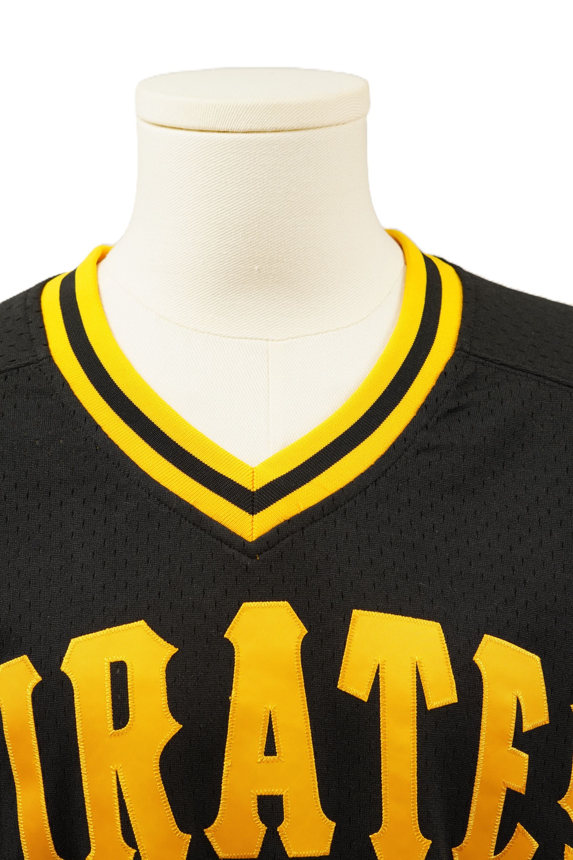 Primo piano dello scollo a V con strisce gialle e nere e della scritta Pirates applicata sul petto della maglia da baseball.