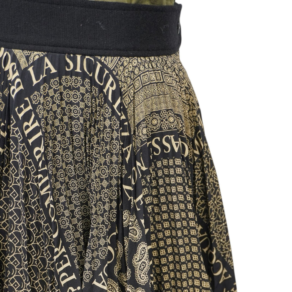 Inquadratura ravvicinata del tessuto con la celebre scritta ironica Moschino e i motivi geometrici in stile barocco.