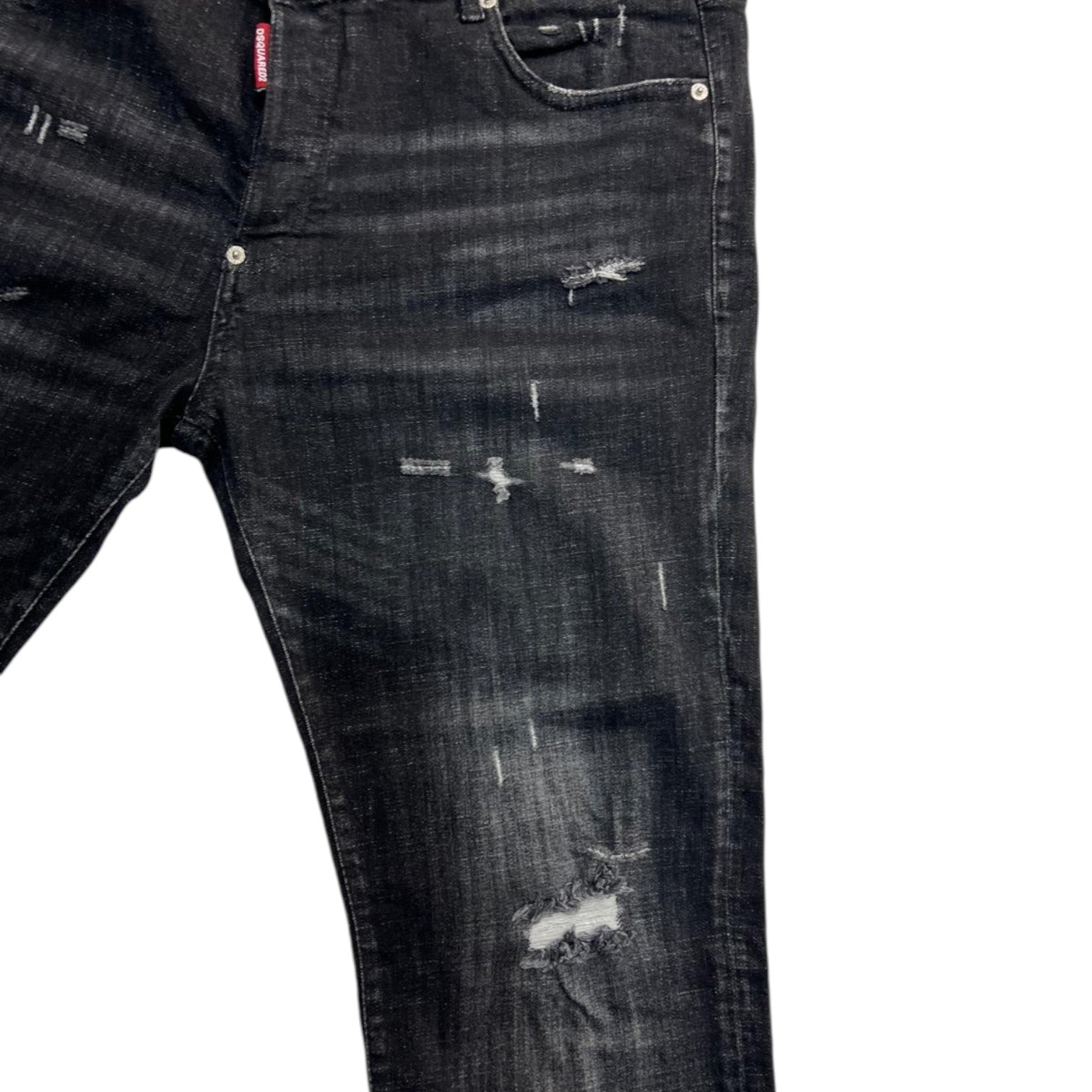 Primo piano della lavorazione artigianale con strappi riparati e baffature sulla coscia dei jeans.