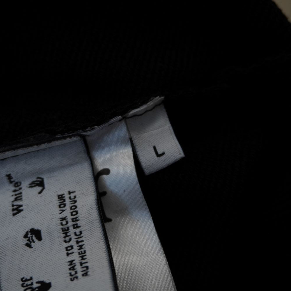Primo piano del tab bianco interno che indica la taglia L della felpa Off-White