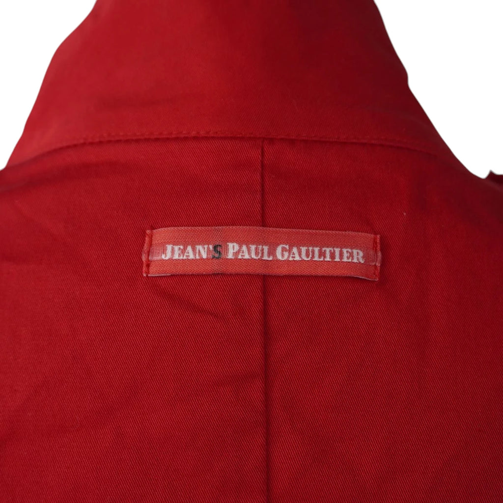 Dettaglio ravvicinato della targhetta rettangolare rossa Jeans Paul Gaultier cucita sulla schiena sotto il colletto.