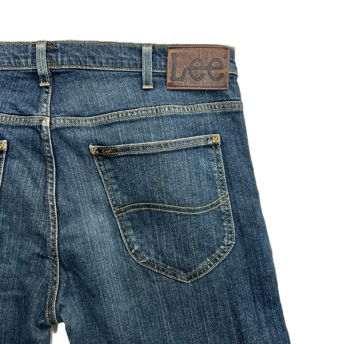Primo piano della tasca posteriore destra dei jeans Lee con la tipica cucitura a onda e la salpa in pelle sul passante.