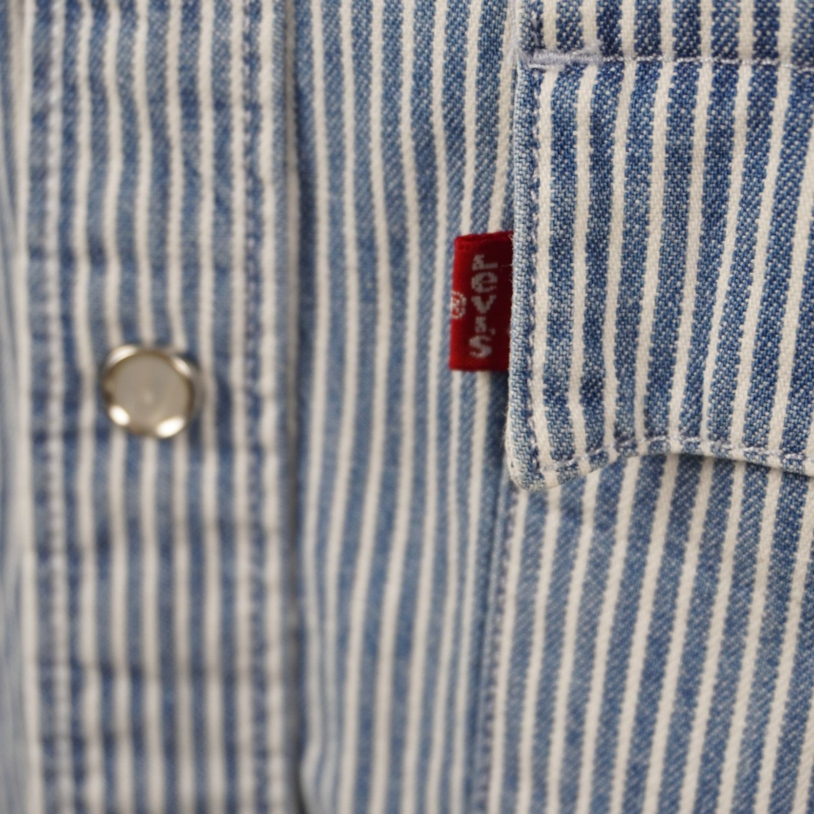 Dettaglio macro della tasca sul petto con bottone a pressione e iconica etichetta Red Tab Levi's