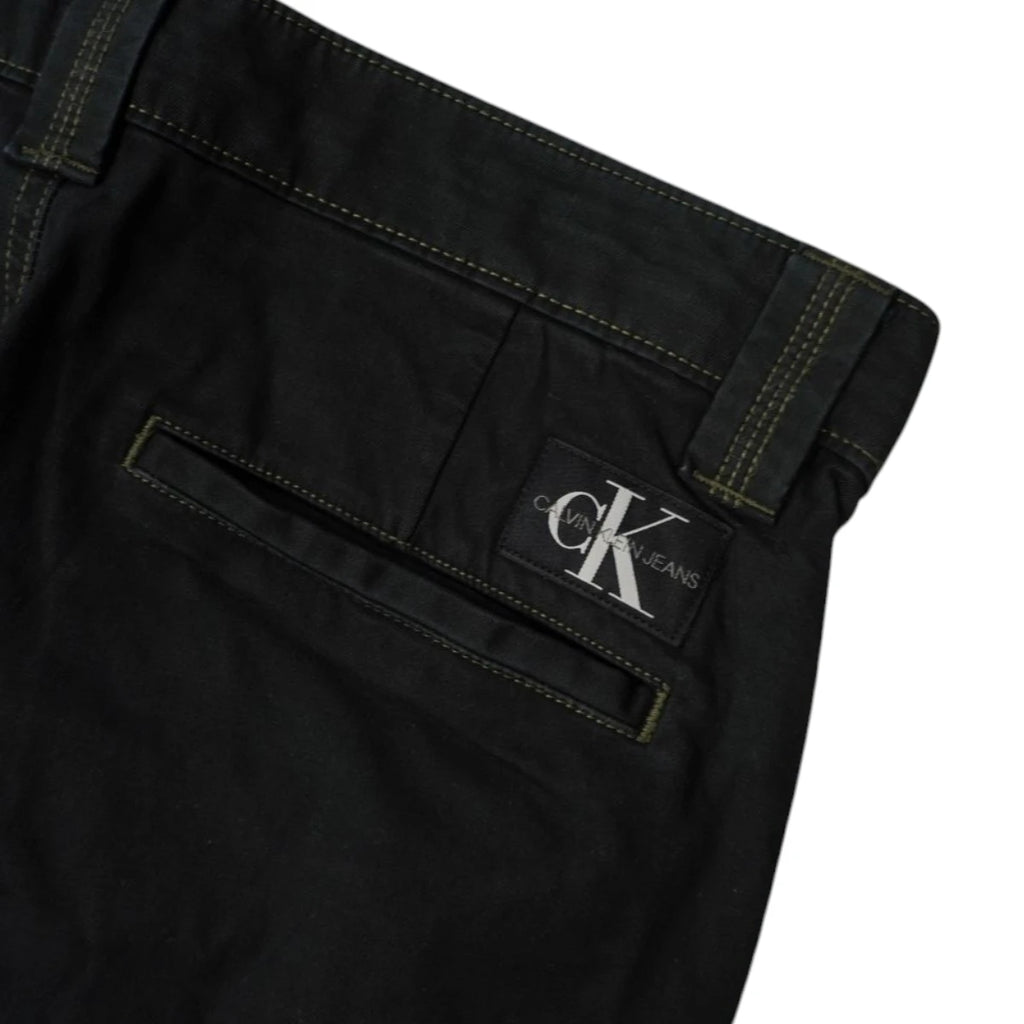 Dettaglio della tasca posteriore a filetto e della patch con logo monogramma CK ricamato