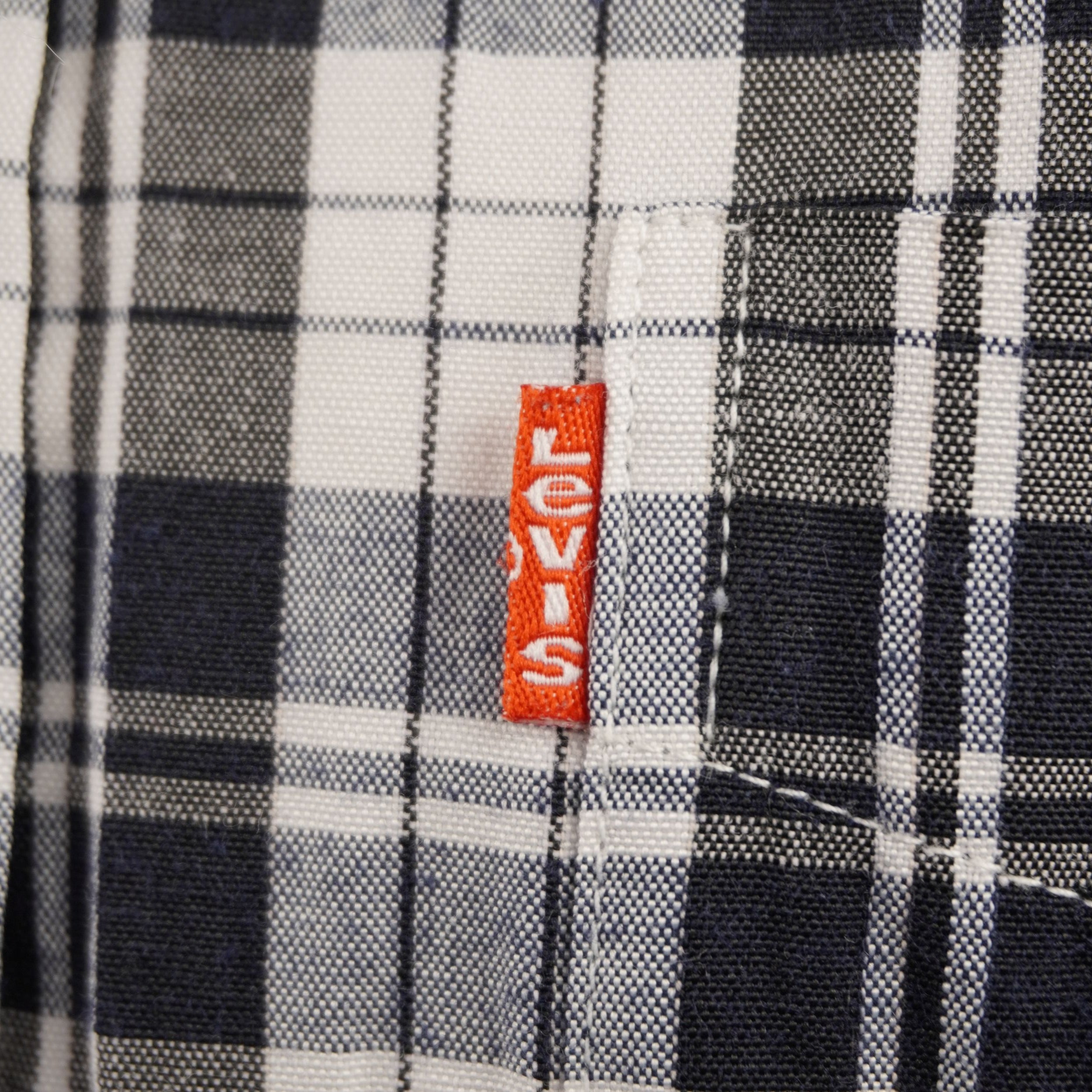Primo piano del taschino sul petto con la storica etichetta arancione Levi's Orange Tab cucita sul lato di una camicia scozzese.