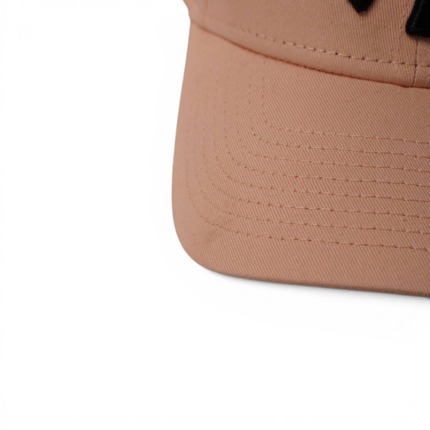  Primo piano ravvicinato delle 8 file di cuciture parallele sulla visiera curva preformata di un cappellino New Era rosa.