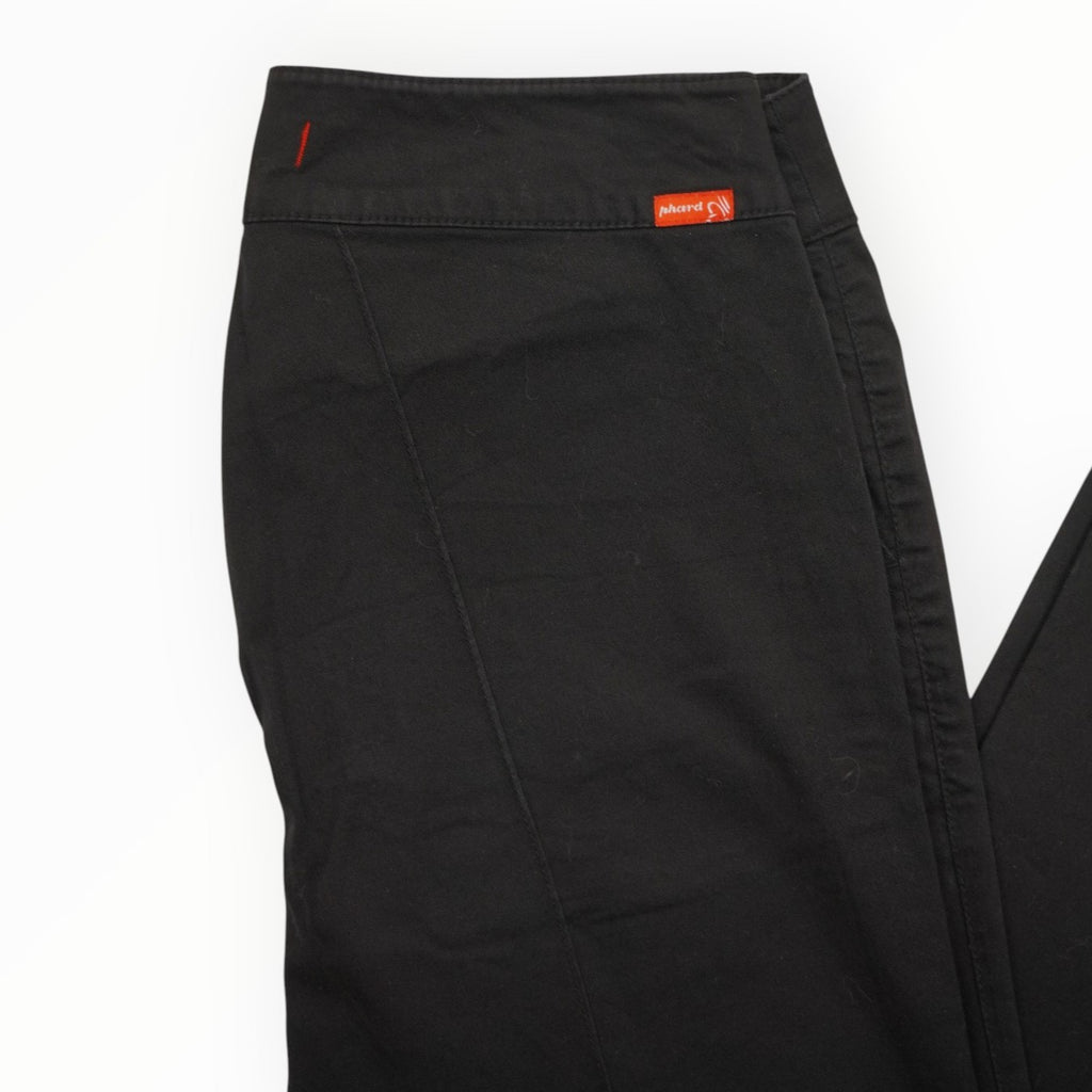  Dettaglio ravvicinato della vita medio-bassa dei pantaloni neri con il caratteristico tag arancione del brand Phard Jeans sul retro.