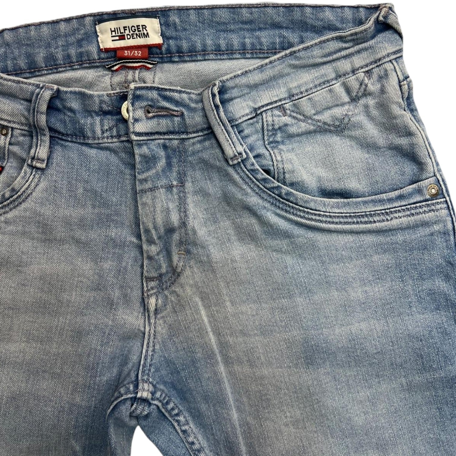 Dettaglio frontale della vita dei jeans con focus sulla taschina portamonete e l'area della patta.