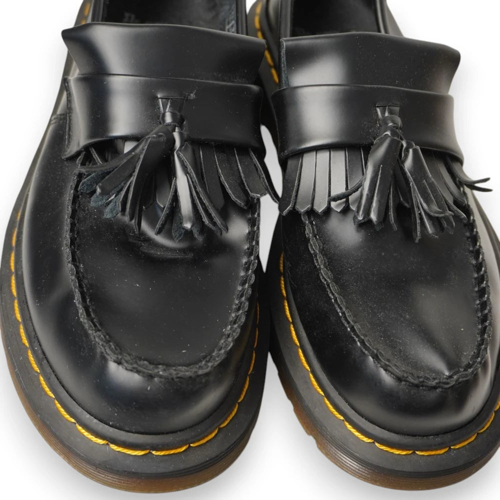 Primo piano macro delle doppie nappe e delle frange decorative sulla tomaia dei mocassini Dr. Martens