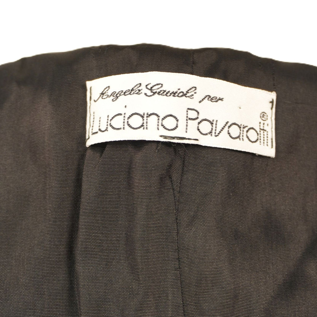 Etichetta interna in tessuto bianco della linea archivio Angela Gavioli per Luciano Pavarotti cucita sulla fodera nera della giacca.