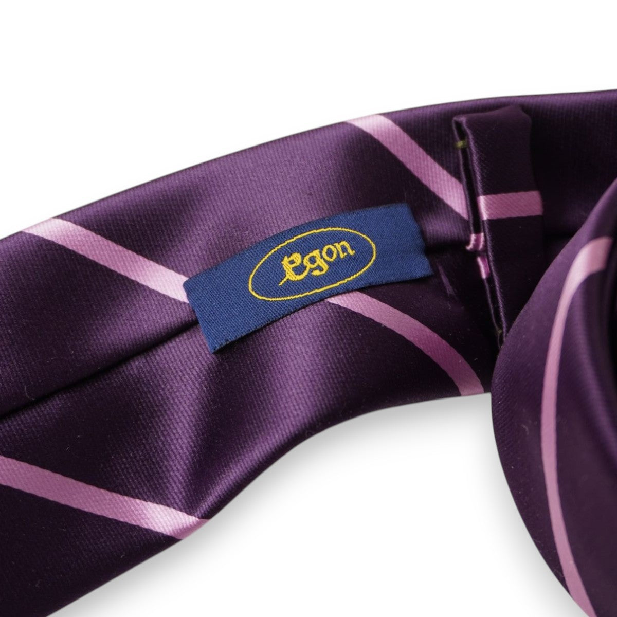 Etichetta istituzionale blu navy con brand Egon inserita nell'asola ovale gialla sul retro della cravatta vintage.