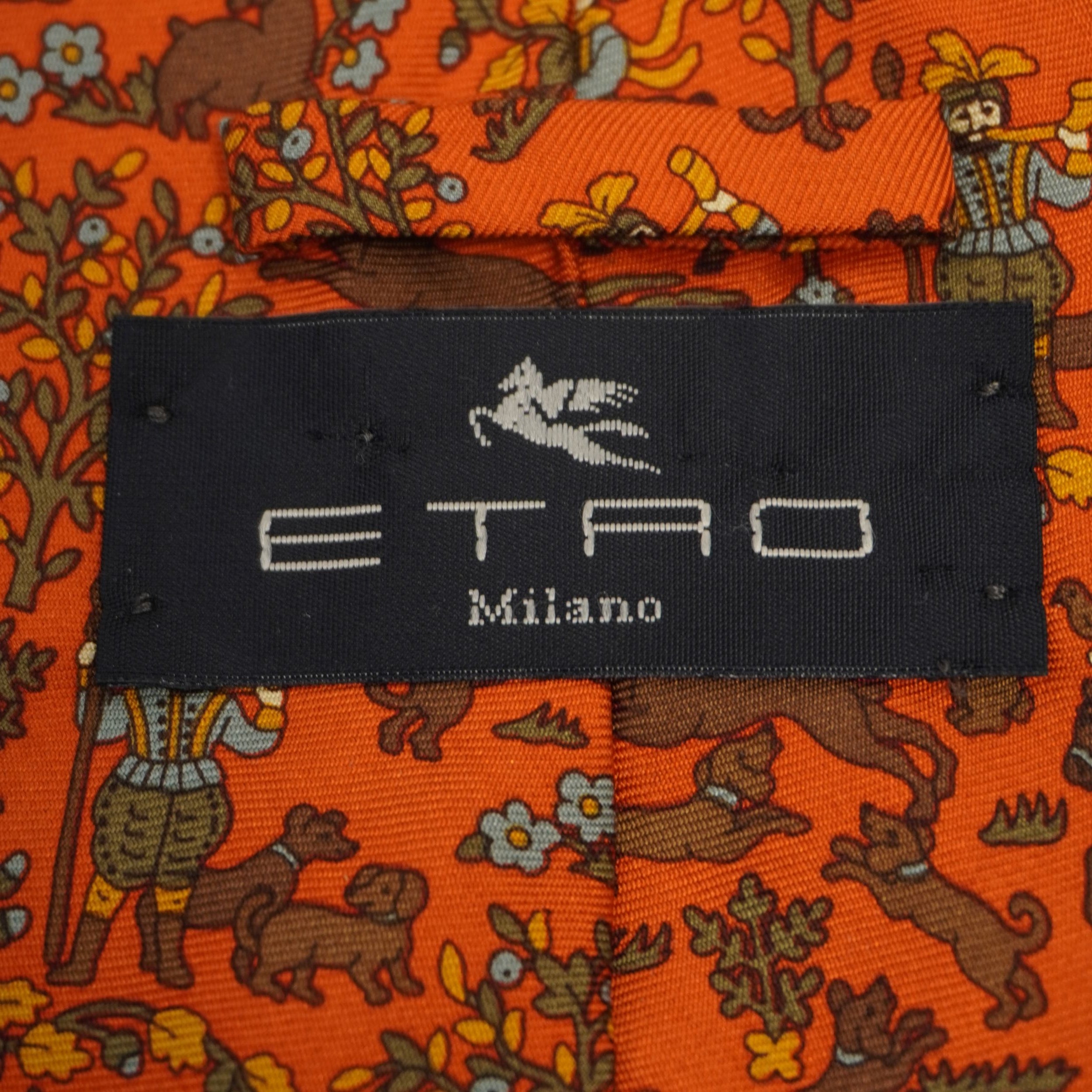 Macro dell'etichetta nera d'autenticità Etro Milano cucita sul retro della cravatta vintage in seta arancione.
