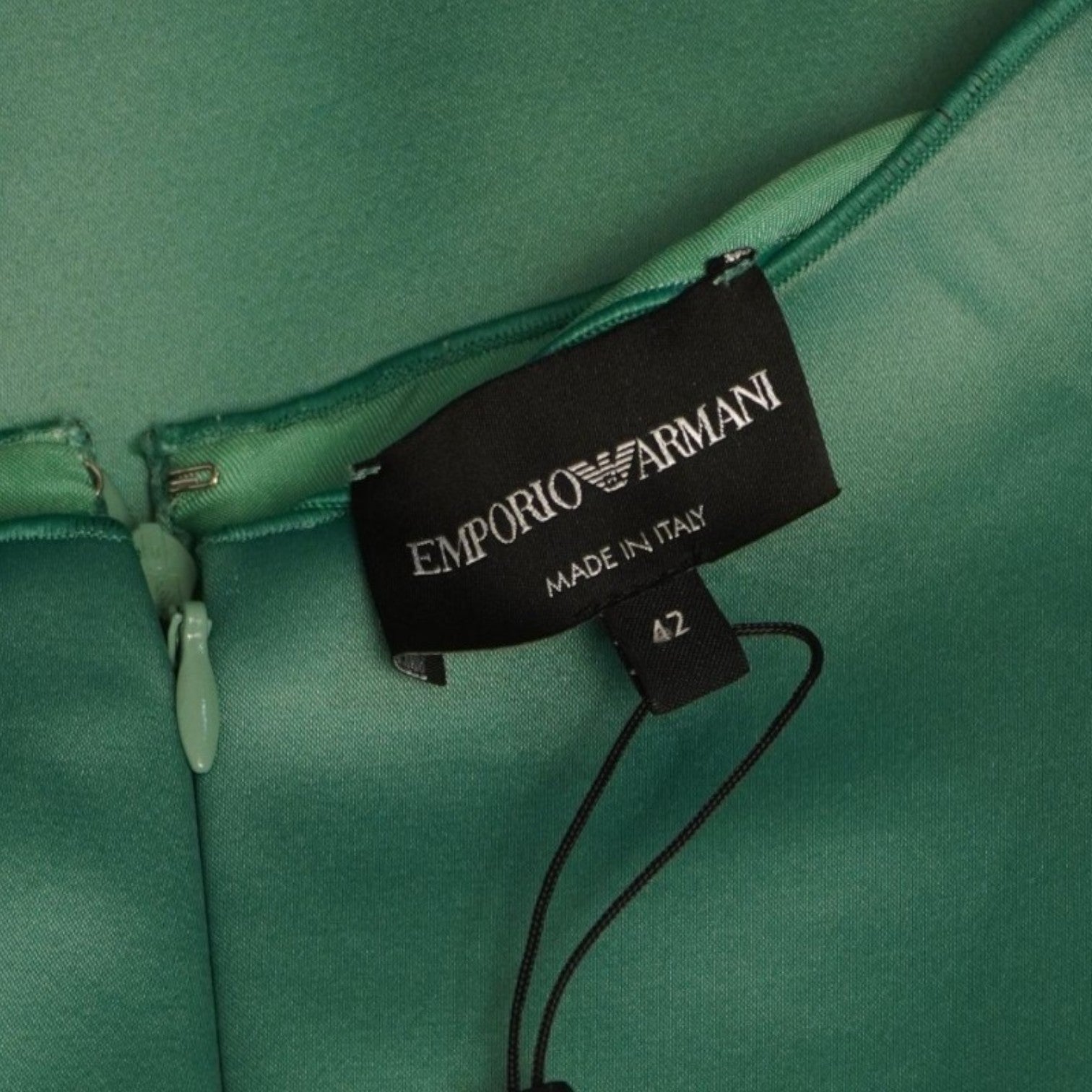 Primo piano dell'etichetta interna nera rettangolare con il logo Emporio Armani cucita vicino alla cerniera.
