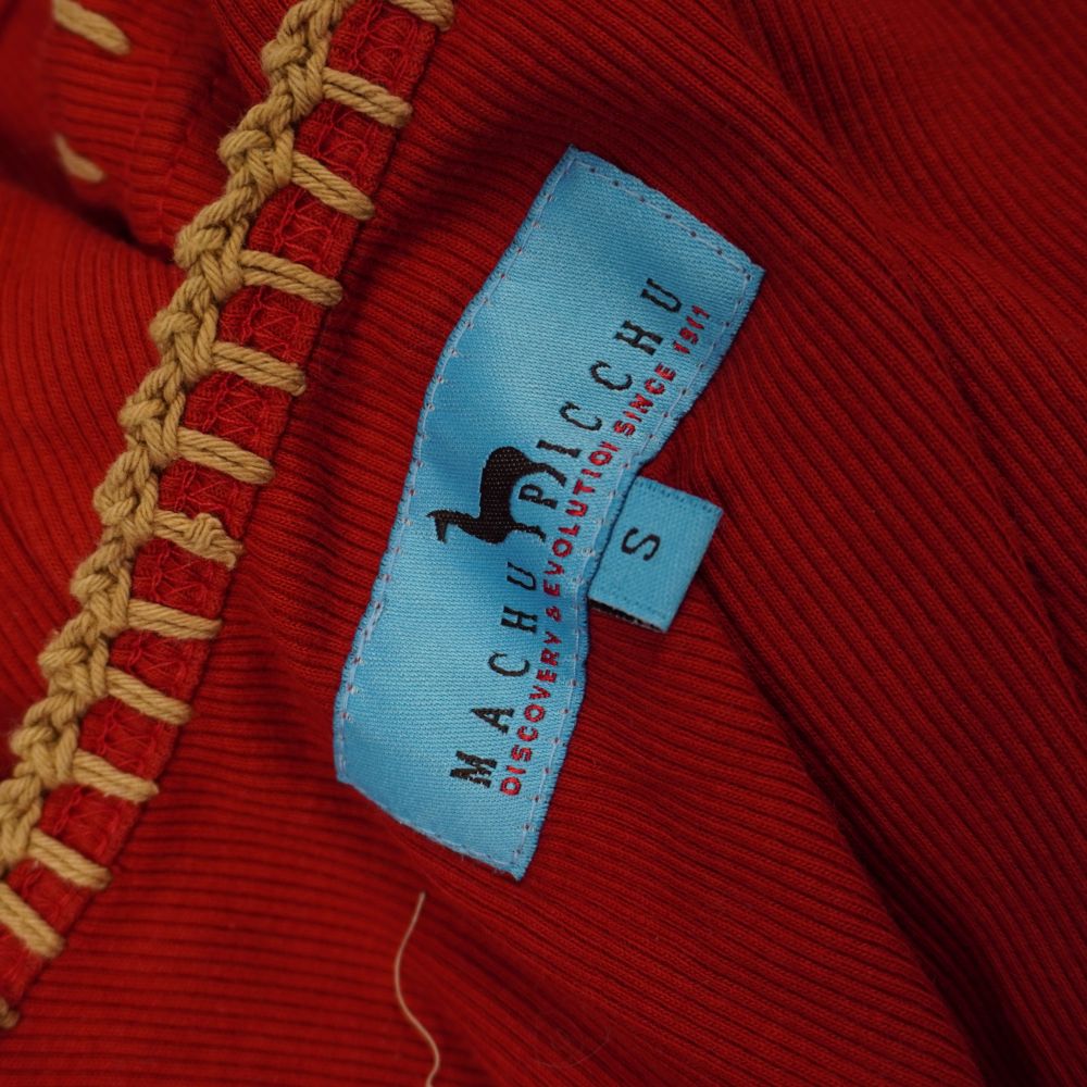  Primo piano dell'etichetta interna in tessuto azzurro del brand Machu Picchu Discovery and Evolution con logo del lama e indicazione della taglia S.