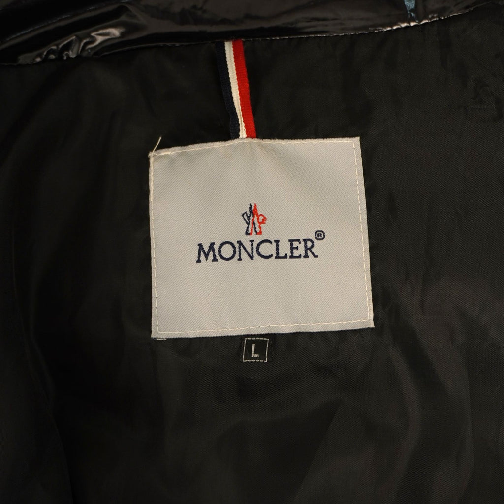 Primo piano dell'etichetta interna quadrata bianca con il logo ricamato Moncler e il passante con i colori della bandiera francese.
