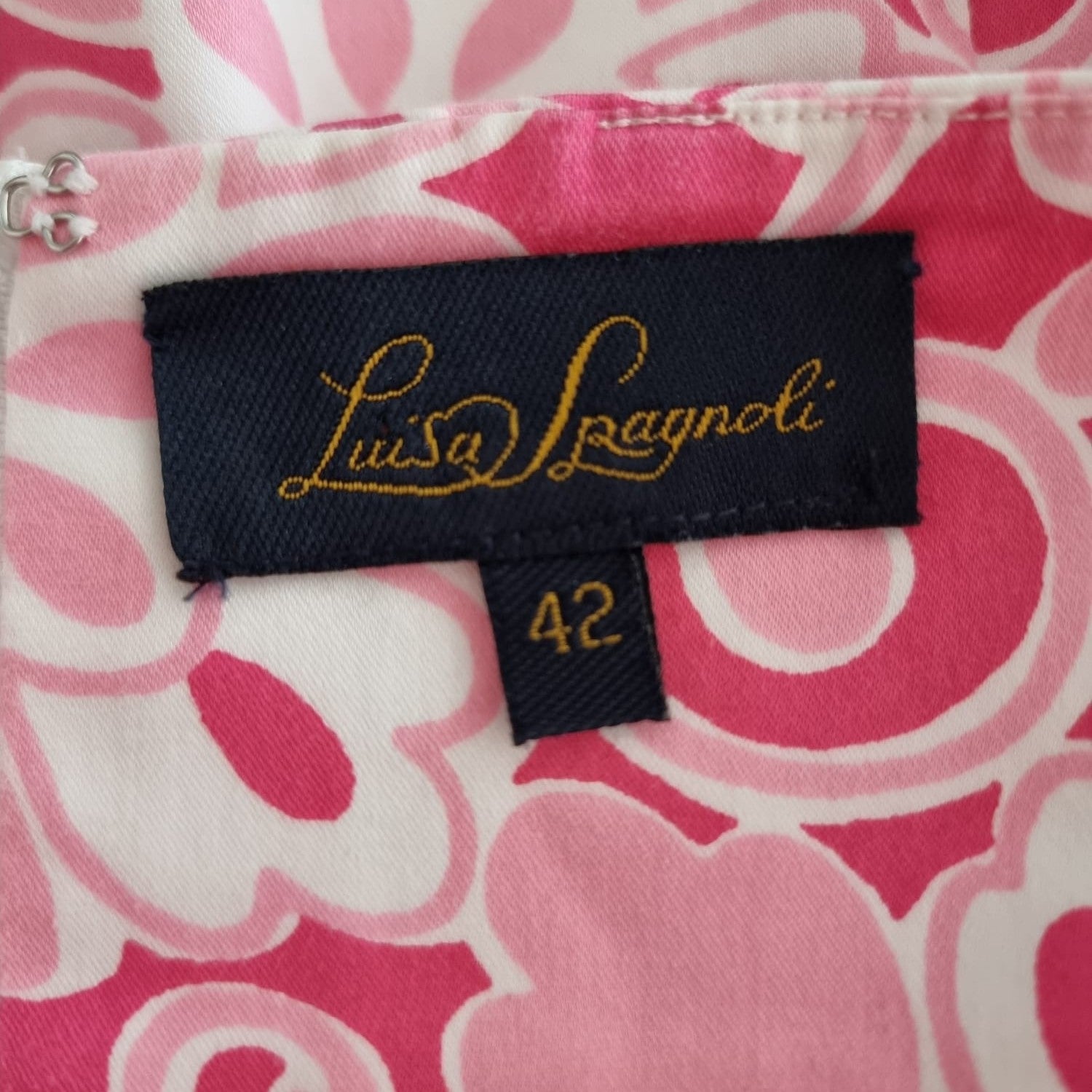 Primo piano dell'etichetta interna in tessuto blu scuro con logo dorato Luisa Spagnoli e indicazione della taglia 42.