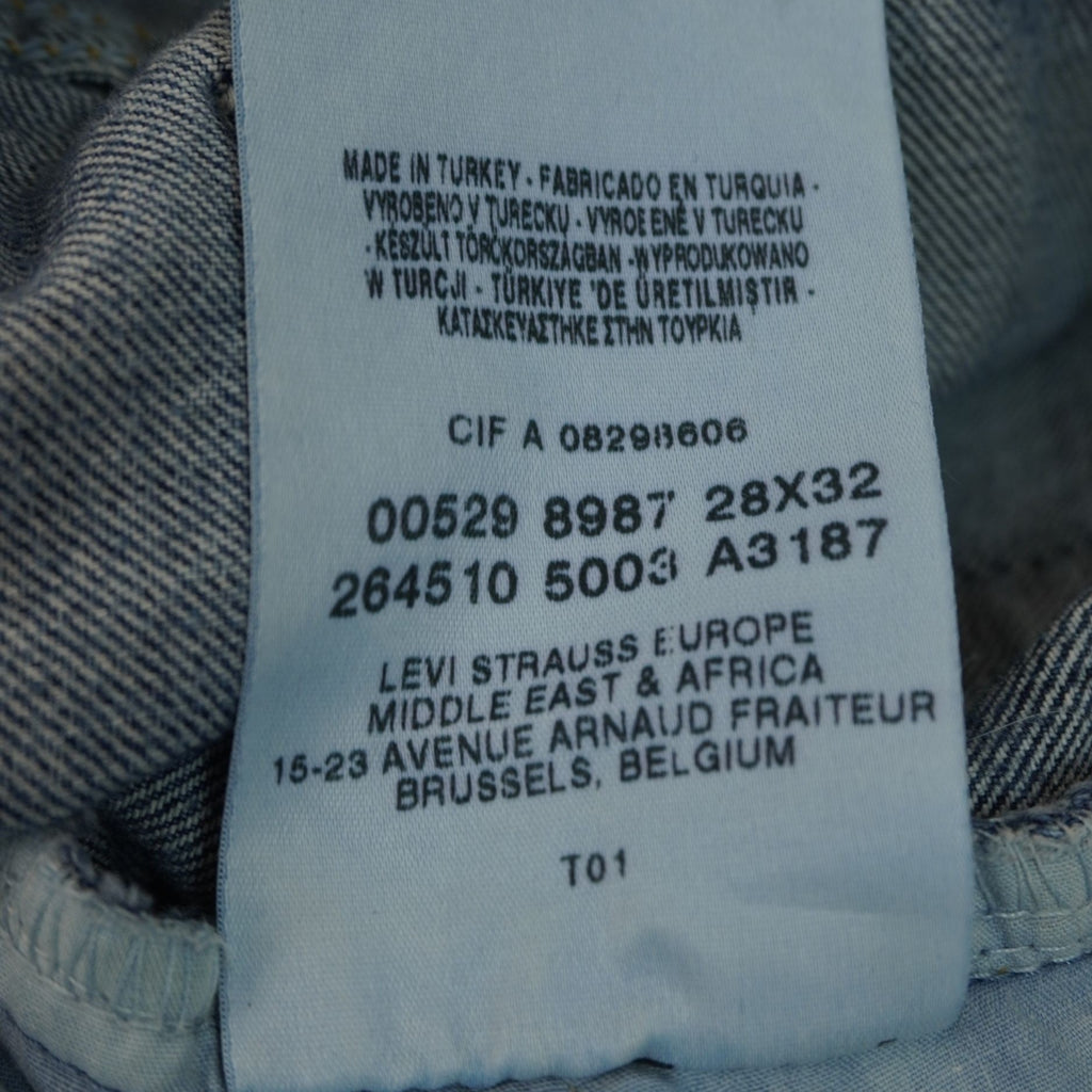 Macro dell'etichetta bianca interna che riporta i codici di serie industriali e i dati di tracciabilità dei jeans.