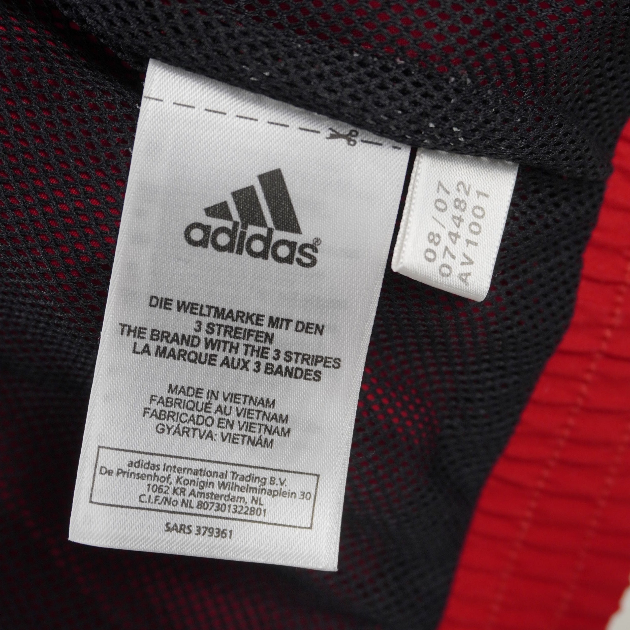 Mini etichetta interna bianca adidas con il codice stile ART 074482 e la data di produzione 08/07.