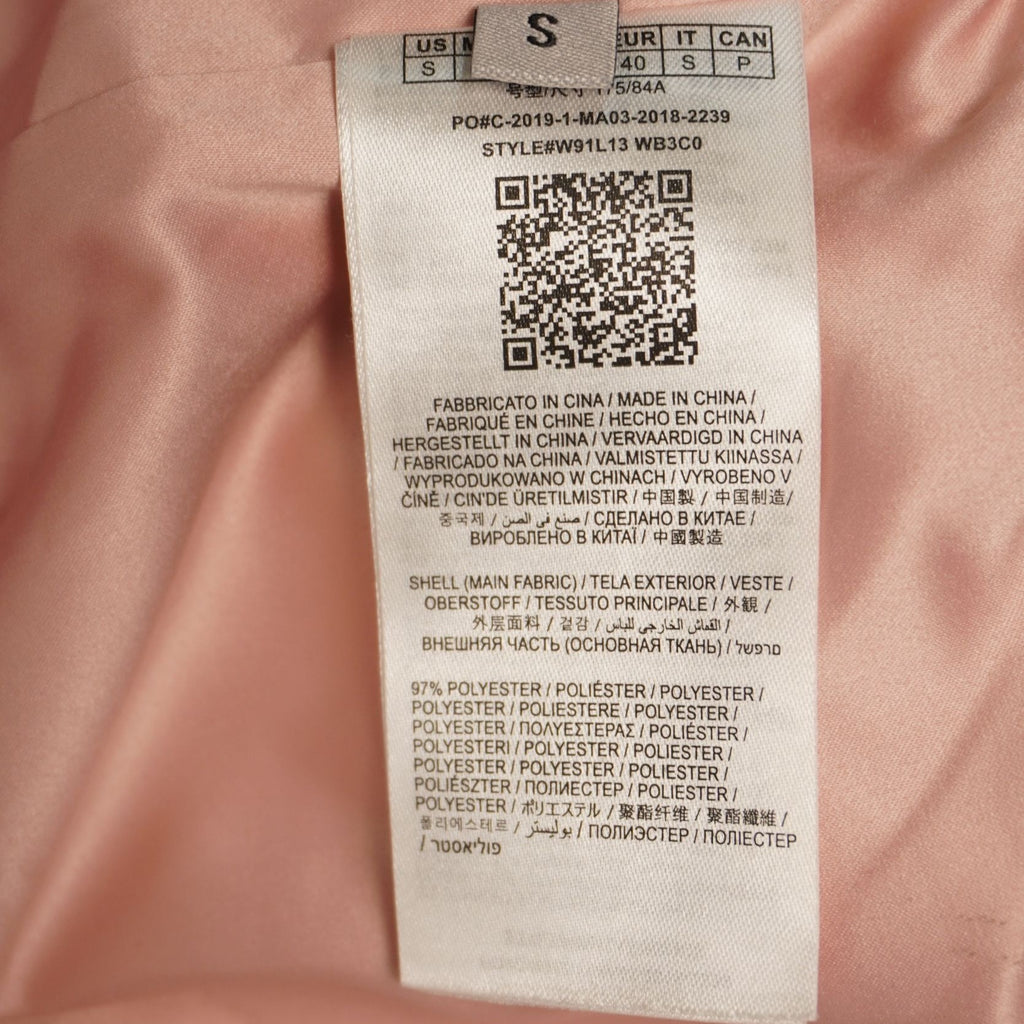 Dettaglio dell'etichetta interna in tessuto bianco stampato che mostra il codice QR per la tracciabilità e l'autenticità del capo.
