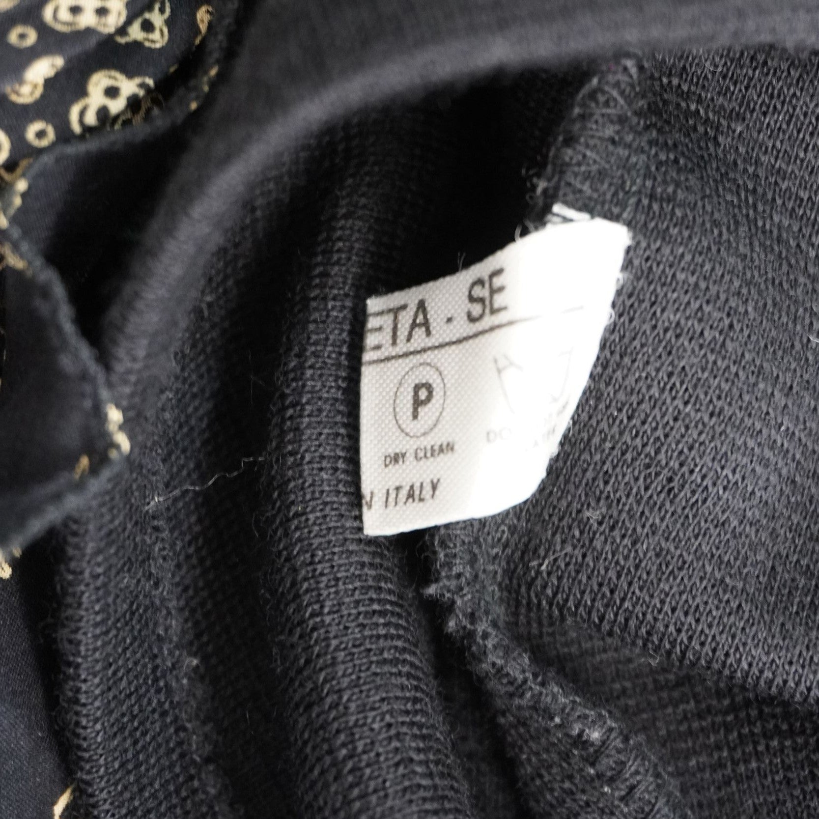 Macro dell'etichetta interna verticale che riporta il codice di serie della casa di moda Moschino per la tracciabilità del capo.