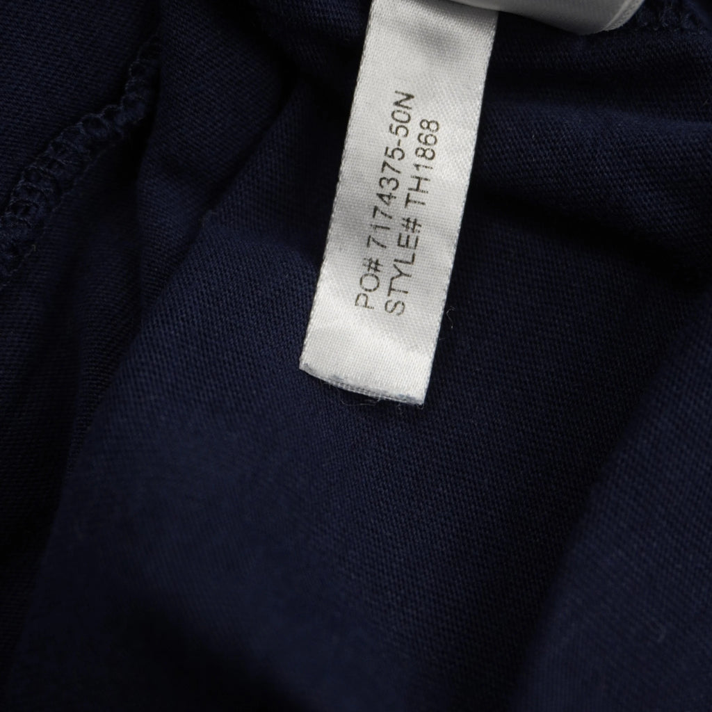 Dettaglio della piccola etichetta interna bianca in tessuto che certifica l'autenticità del capo, con i codici identificativi PO 7174375-50N e STYLE TH1868.