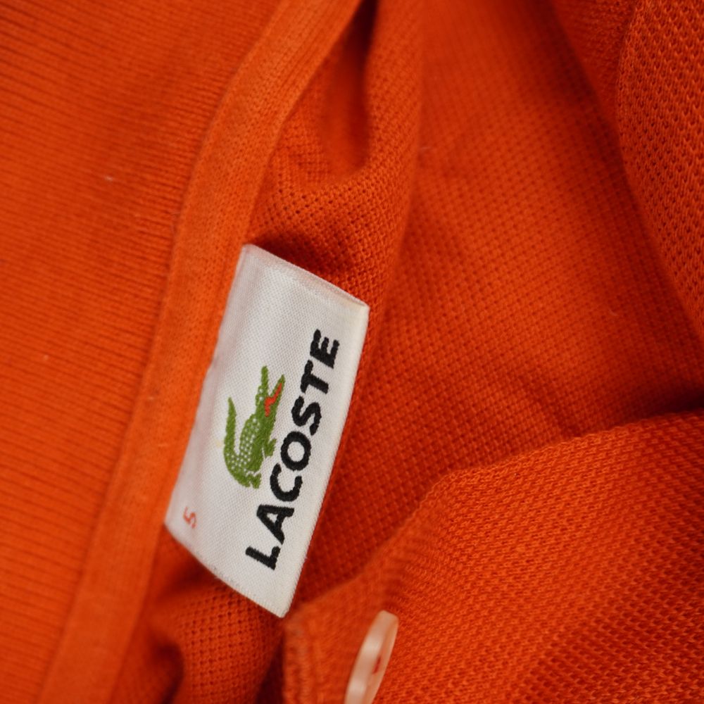 Etichetta interna sul colletto di una polo Lacoste arancione originale con indicazione taglia numero 5 corrispondente a una L