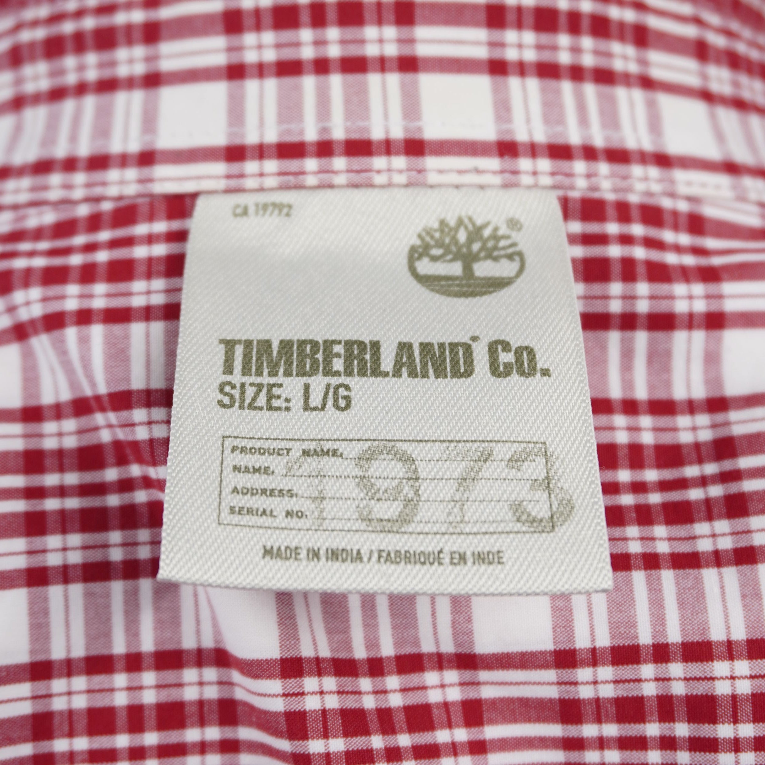  Primo piano dell'etichetta sul colletto Timberland Co. che mostra la taglia L G, la grafica 1973 e la dicitura Made in India.