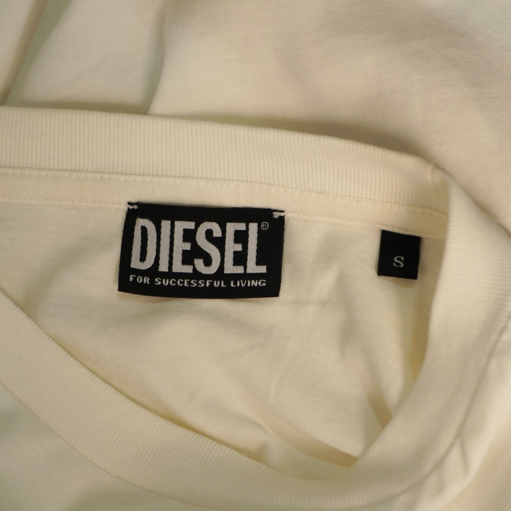 Primo piano dell'etichetta nera con logo Diesel cucita all'interno del colletto e indicazione della taglia S.
