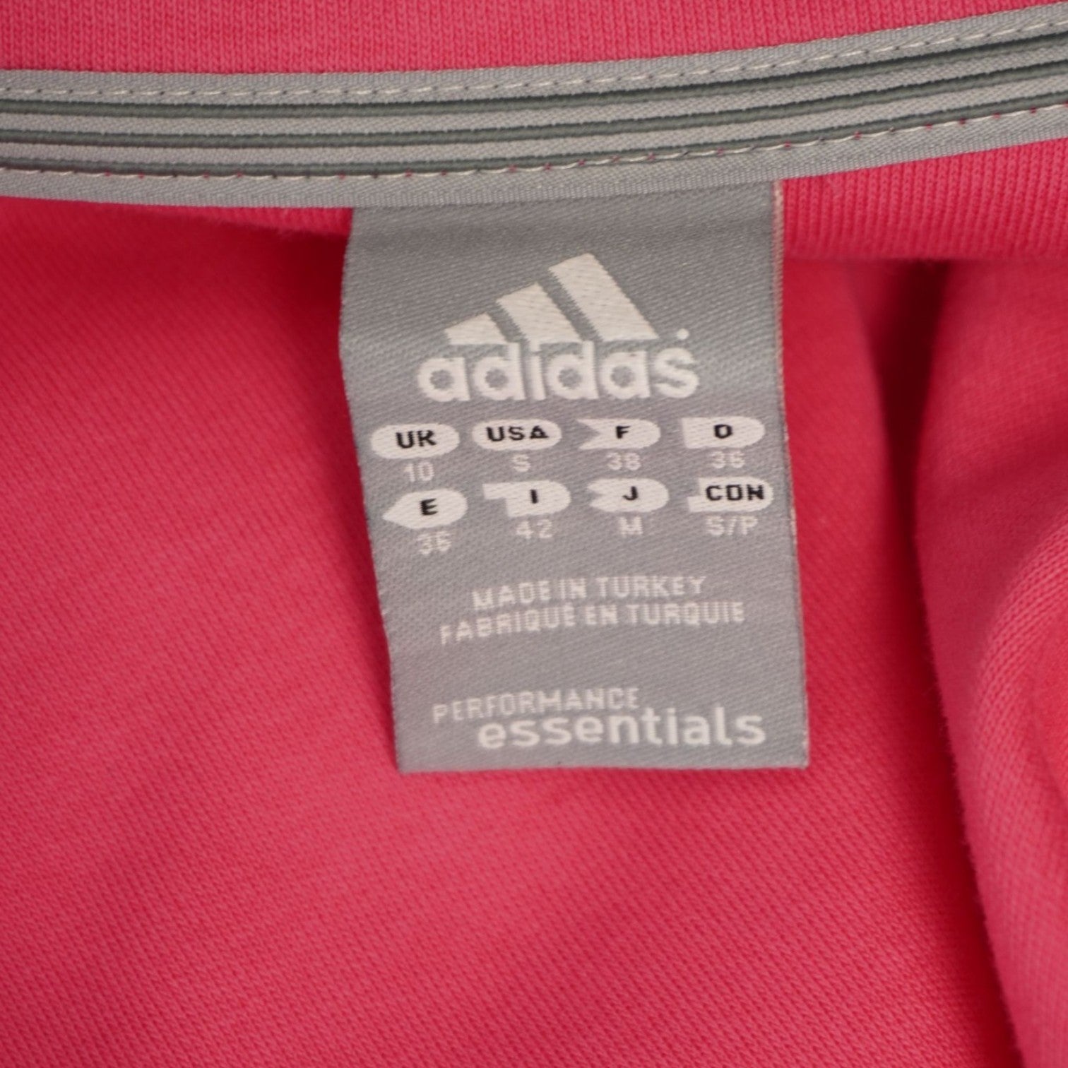 Dettaglio dell'etichetta grigia stampata all'interno del collo con il logo Adidas e le indicazioni della taglia