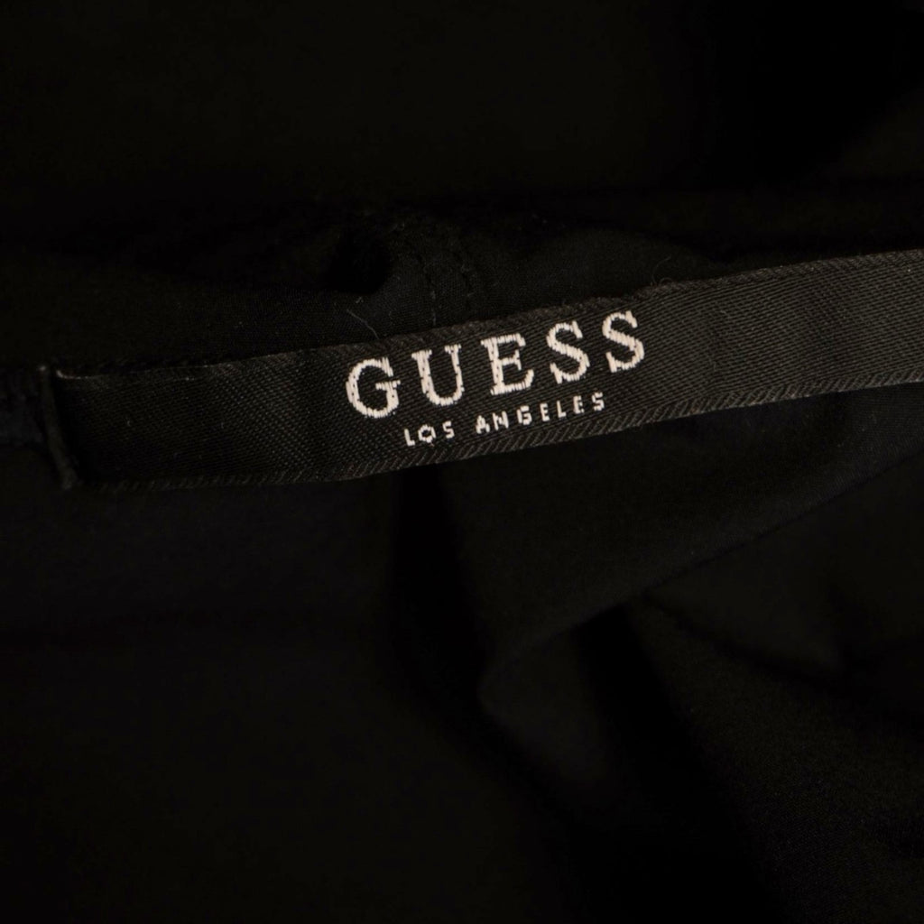 Dettaglio del brand core sul collo interno con la scritta "GUESS Los Angeles" ricamata su fettuccia nera.