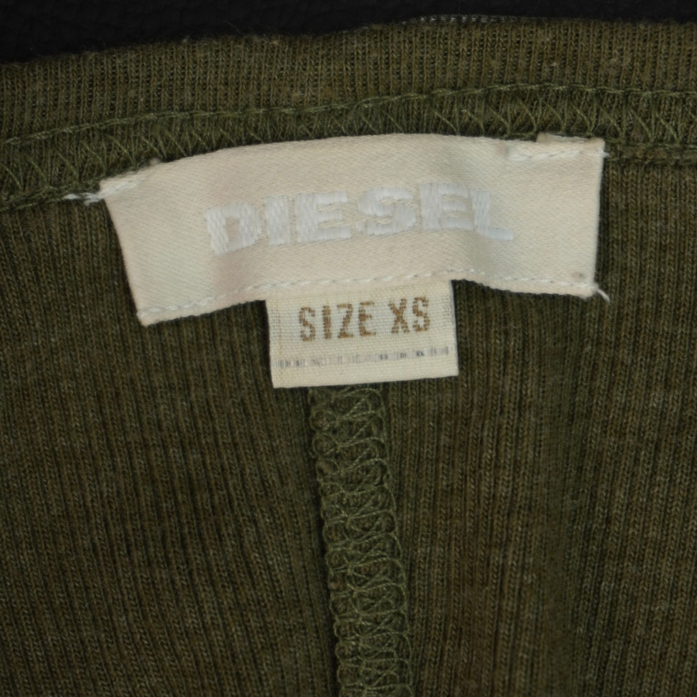 Dettaglio dell'etichetta chiara interna cucita sul collo con il logo Diesel e la taglia XS.