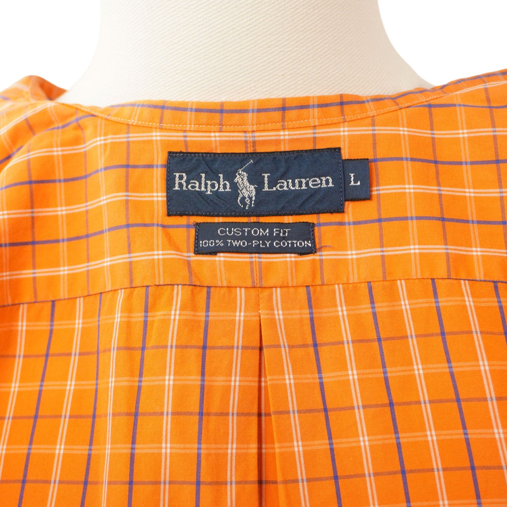 Dettaglio dell'etichetta interna rettangolare blu scuro con il marchio Ralph Lauren e l'indicazione della taglia L cucita sotto il colletto.
