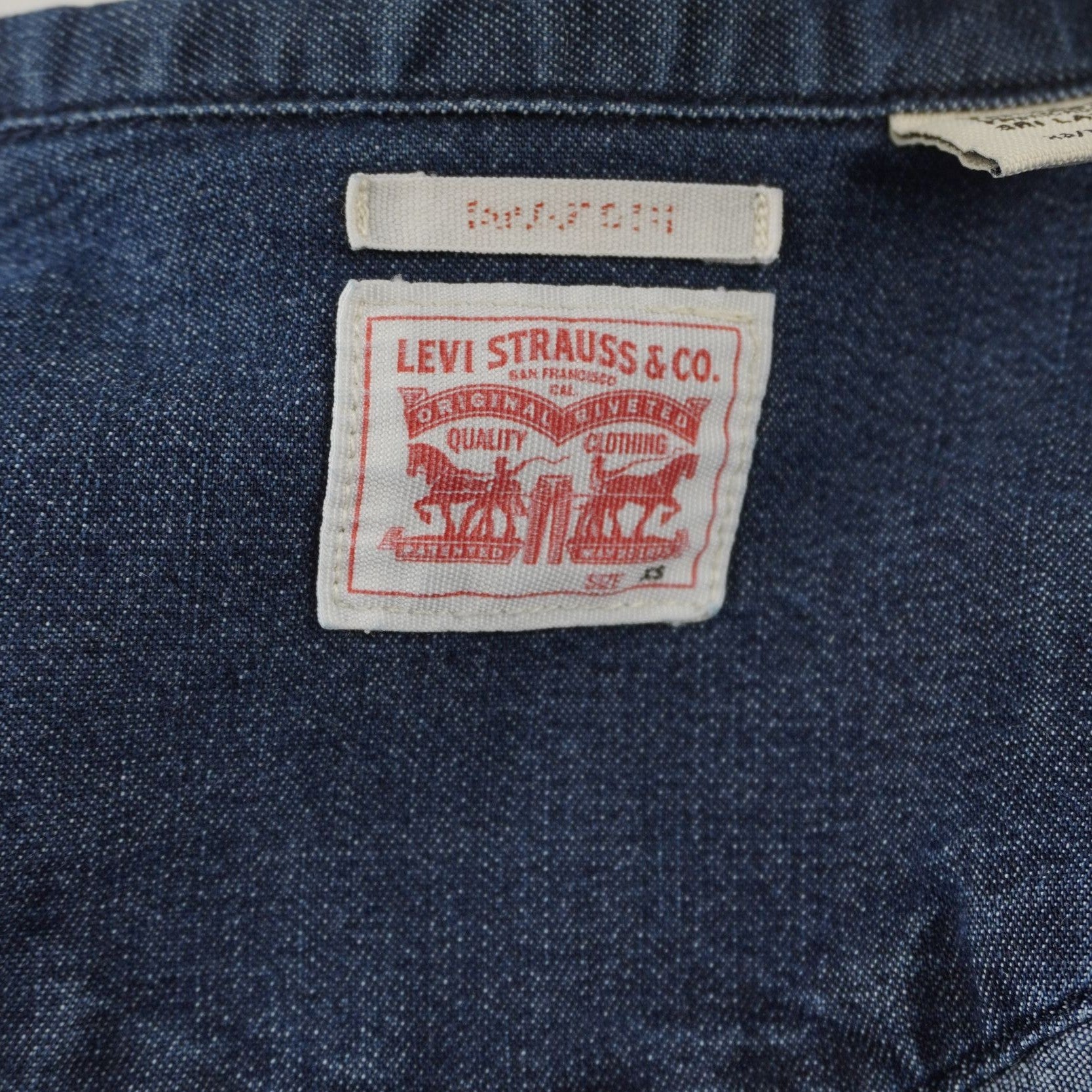 Dettaglio del classico patch bianco interno sul retro del collo con il logo dei due cavalli Levi's.