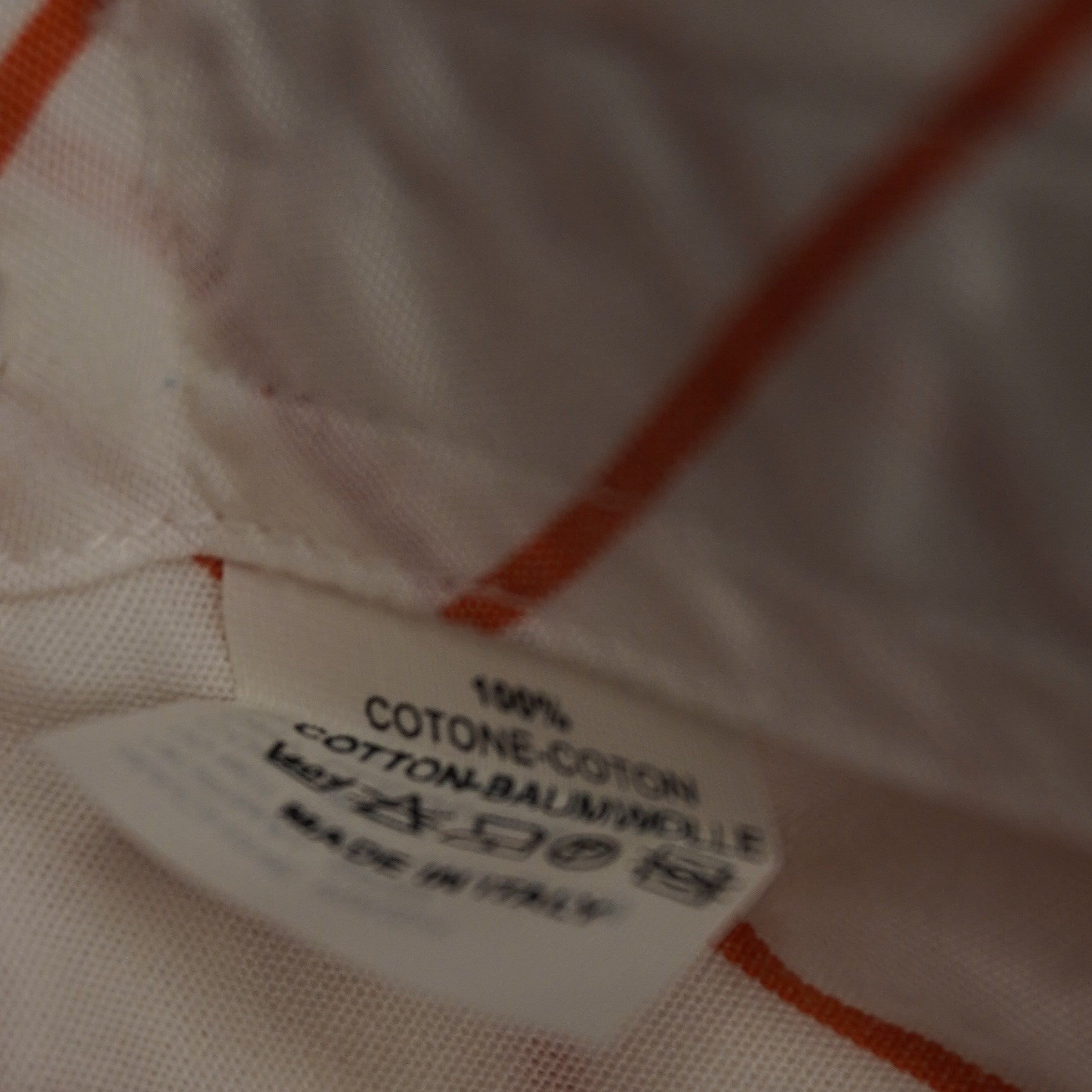 Dettaglio ravvicinato dell'etichetta interna di composizione della camicia Etro che certifica il tessuto 100% cotone e la manifattura Made in Italy con i relativi simboli di lavaggio.