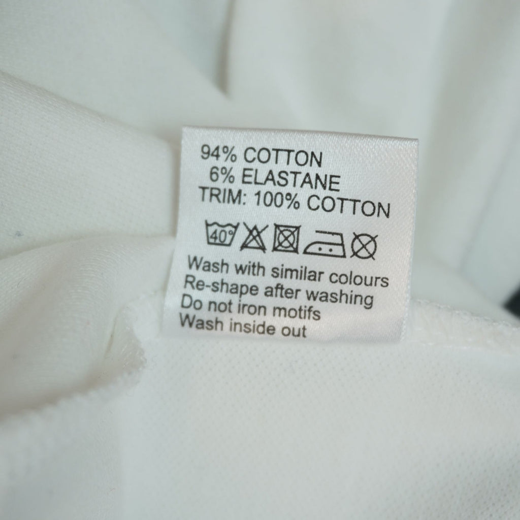 Etichetta interna di lavaggio che indica la composizione in 94% cotone e 6% elastane del corpo del capo.