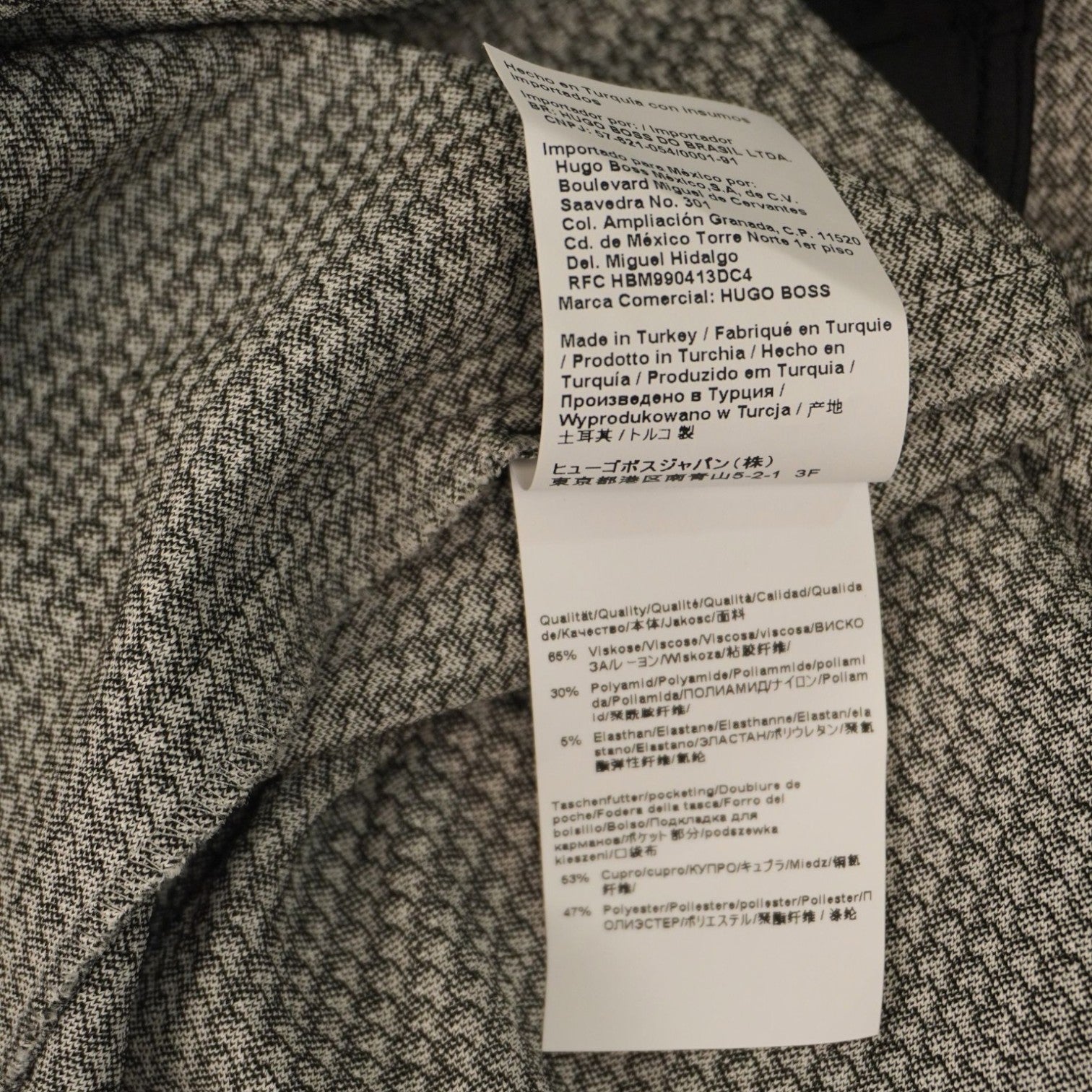 Etichetta interna bianca che riporta la composizione del tessuto in diverse lingue (viscosa, poliammide ed elastan).