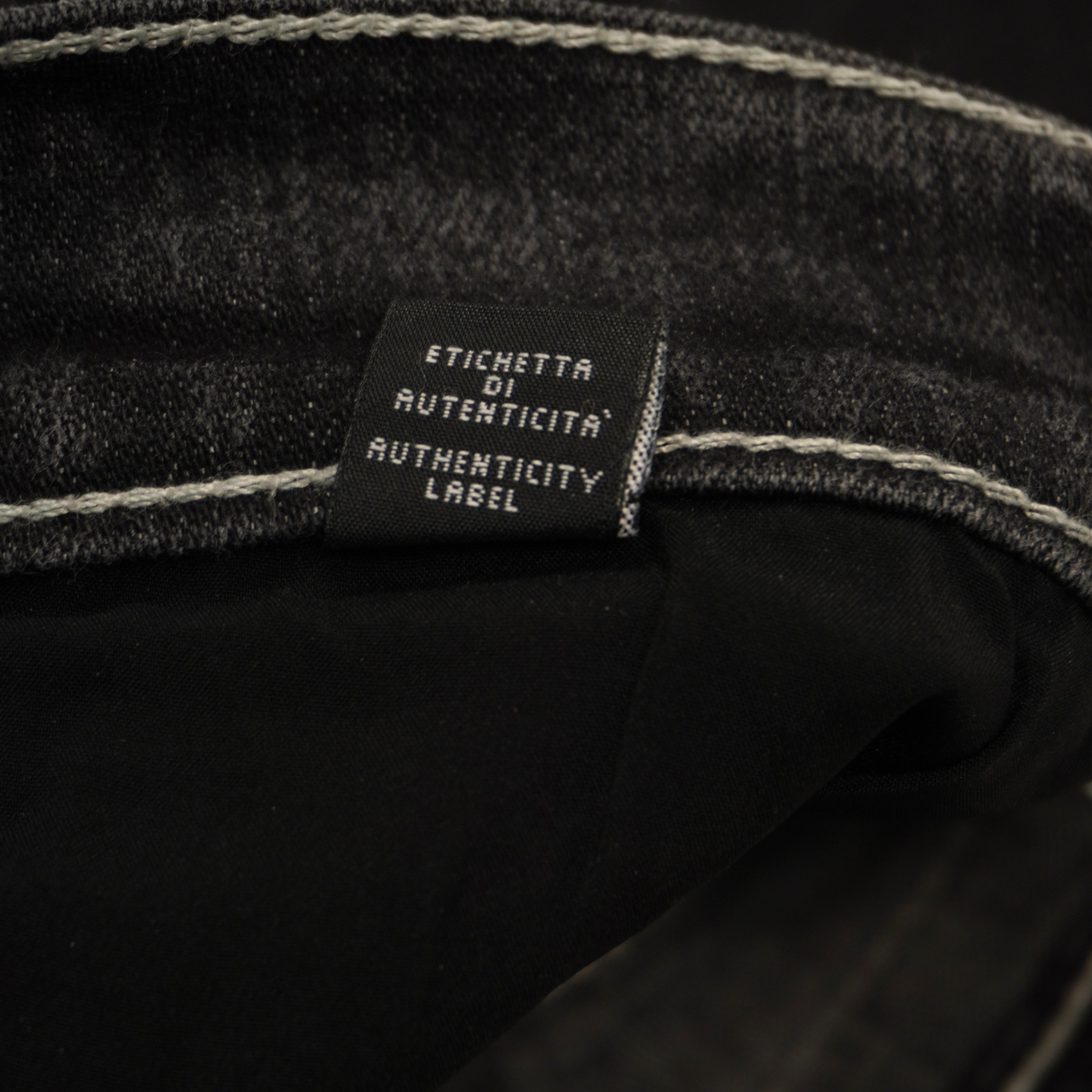 Macro dell'etichetta tecnica interna in tessuto scuro che attesta la composizione dei materiali e la produzione Made in Italy.