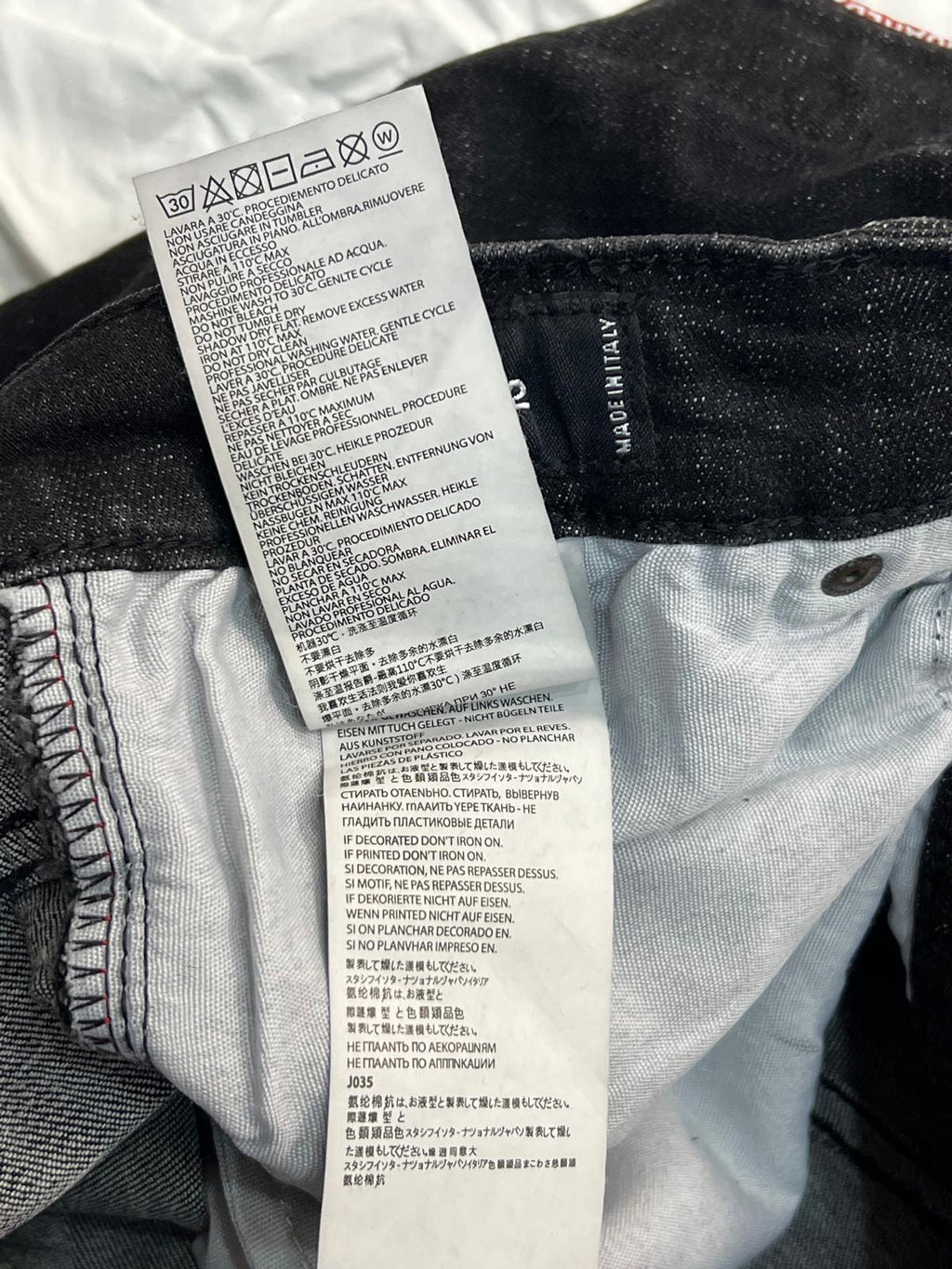 Vista dell'etichetta interna bianca con le istruzioni di lavaggio e l'indicazione della taglia dei pantaloni.