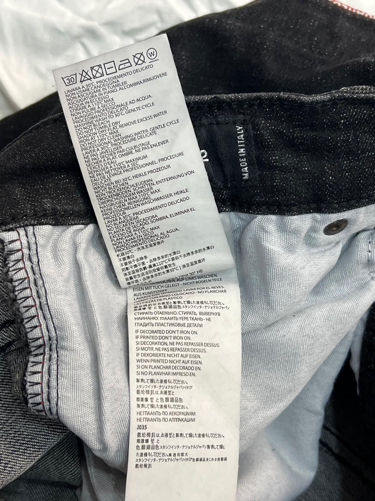 Vista dell'etichetta interna bianca con le istruzioni di lavaggio e l'indicazione della taglia dei pantaloni.