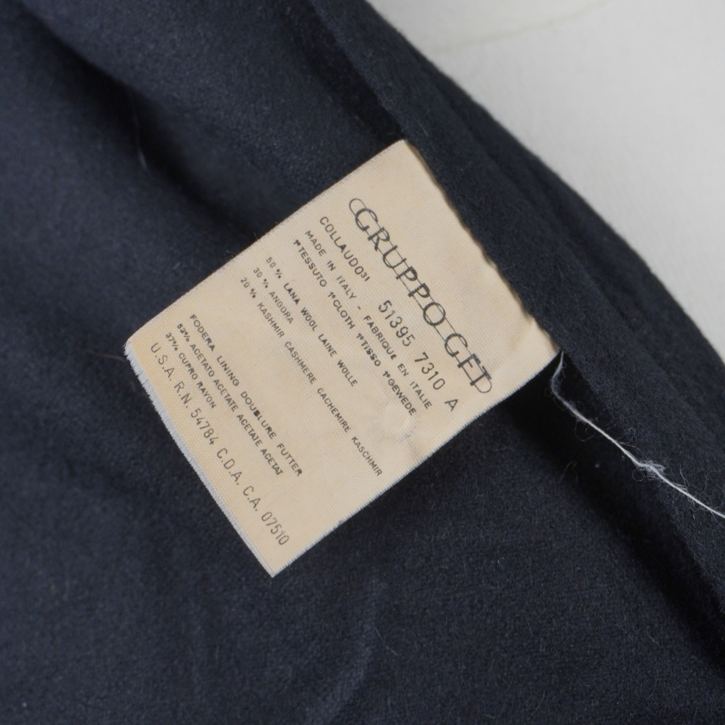 Etichetta di composizione del cappotto Dior che certifica il tessuto in 50% lana, 30% angora e 20% cashmere.