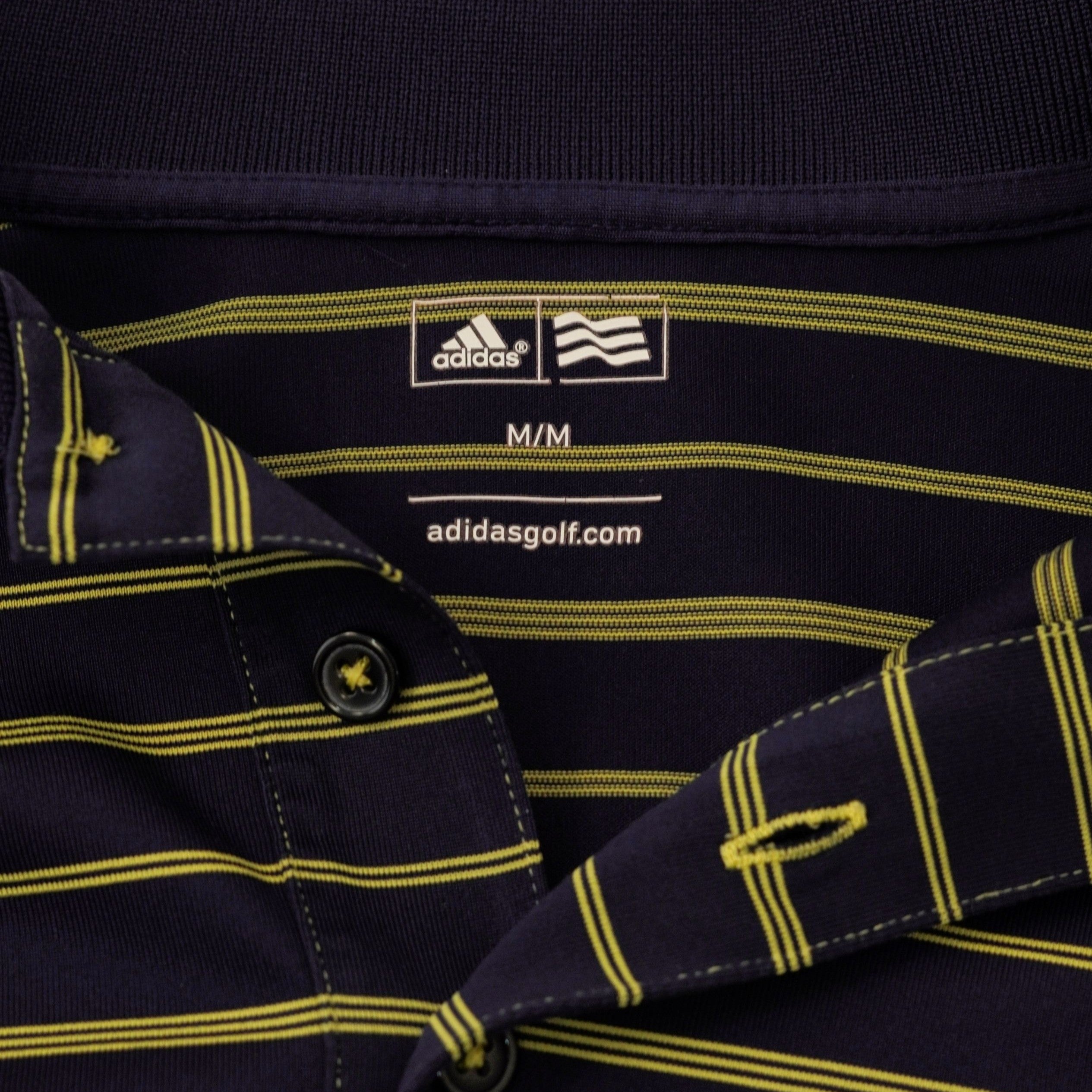 Etichetta interna stampata sul colletto della polo adidas blu navy che attesta l'originalità e indica la taglia M.