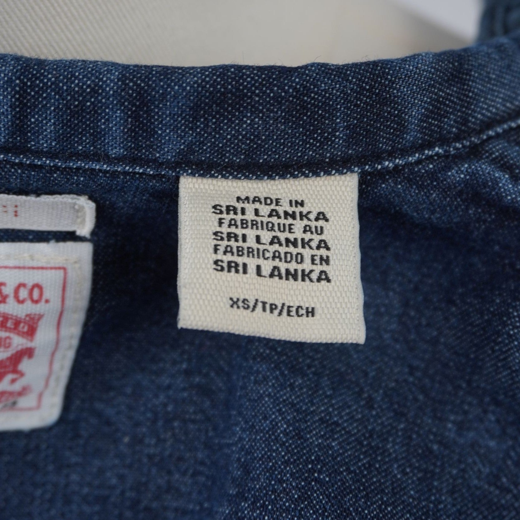 Primo piano dei cartellini in tessuto interni con le scritte istituzionali e di garanzia del brand Levi's.