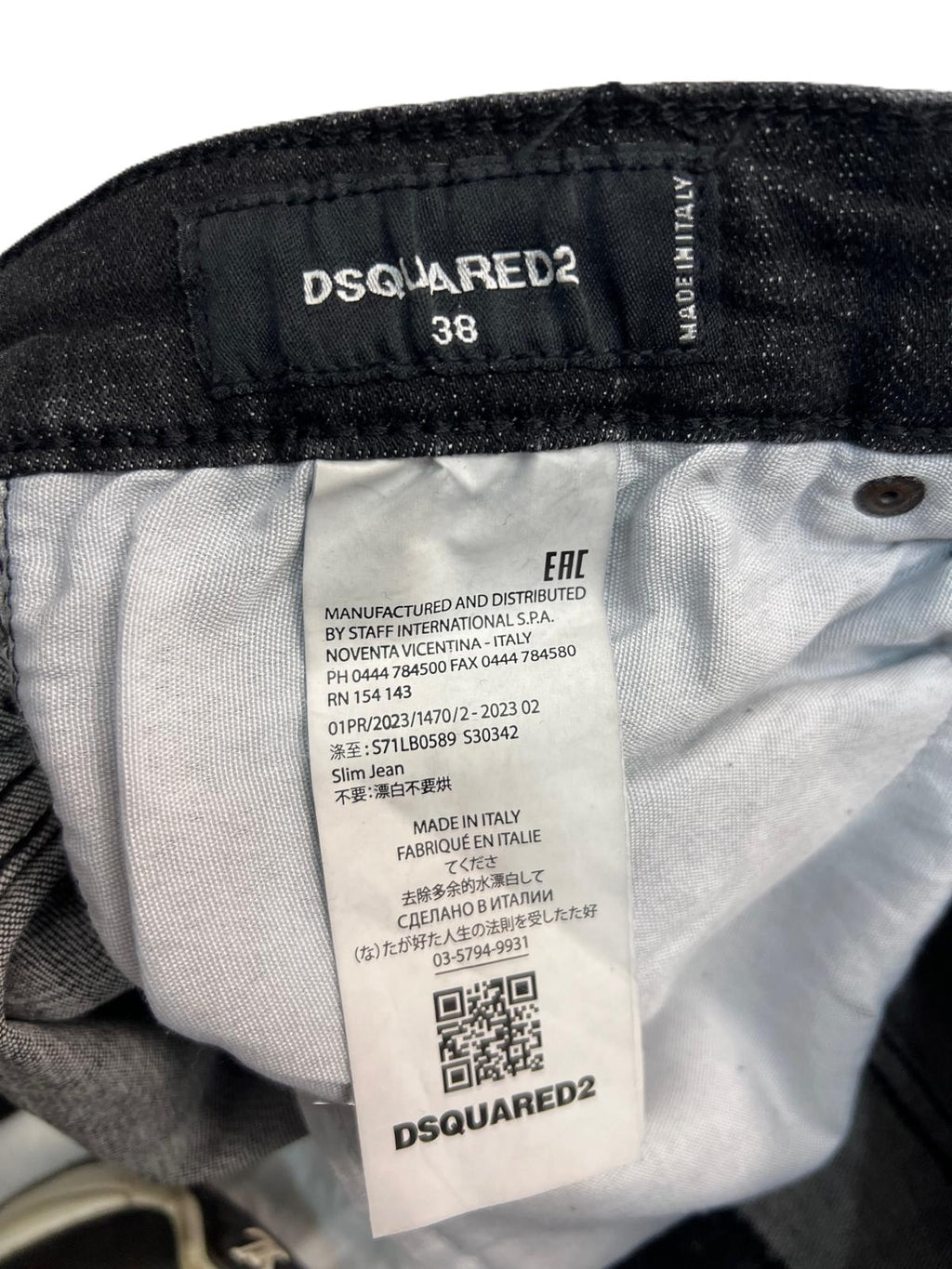 Primo piano dell'etichetta interna in tessuto con il logo del brand e il QR code di tracciabilità.