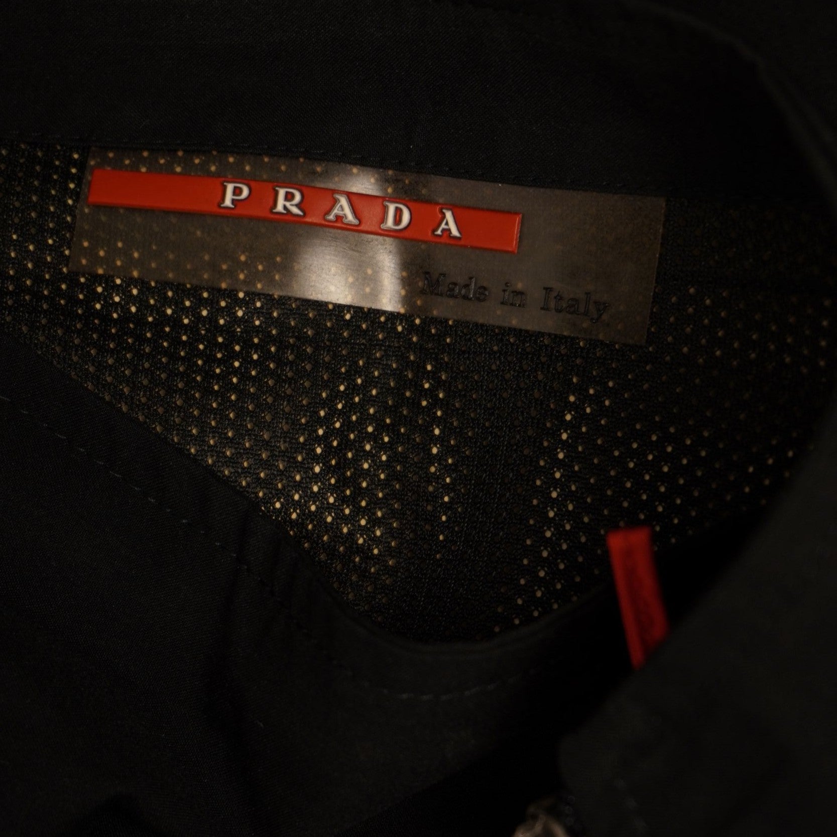 Primo piano dell'interno della gonna nera con fodera tecnica traspirante e targhetta interna originale Prada Milano.