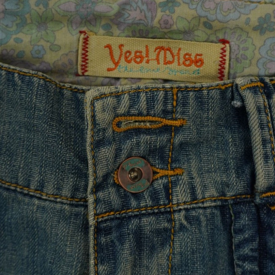 Dettaglio dell'etichetta in tessuto Yes Miss e del bottone sostitutivo sulla chiusura frontale del jeans