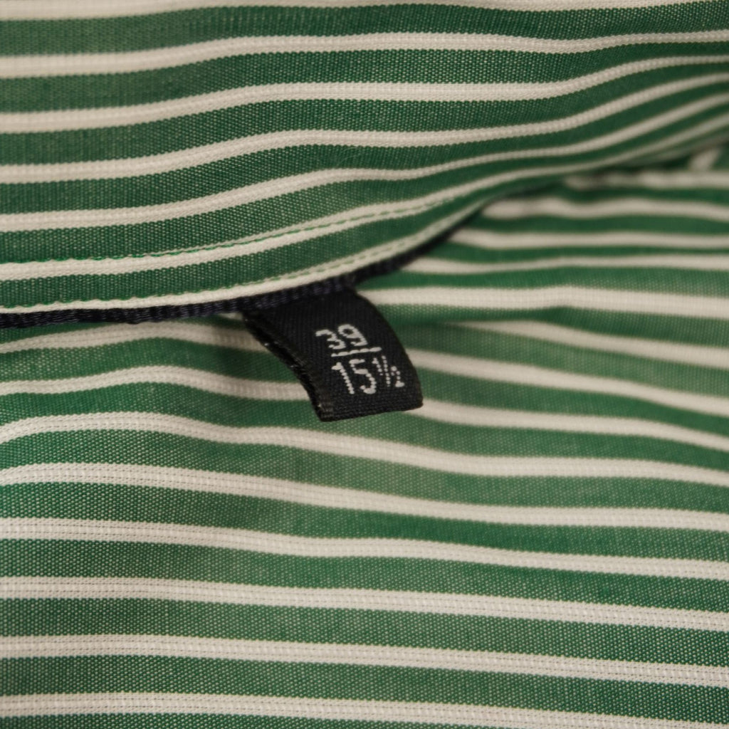 Dettaglio dell'etichetta interna nera cucita sul colletto della camicia a righe che indica la taglia M.