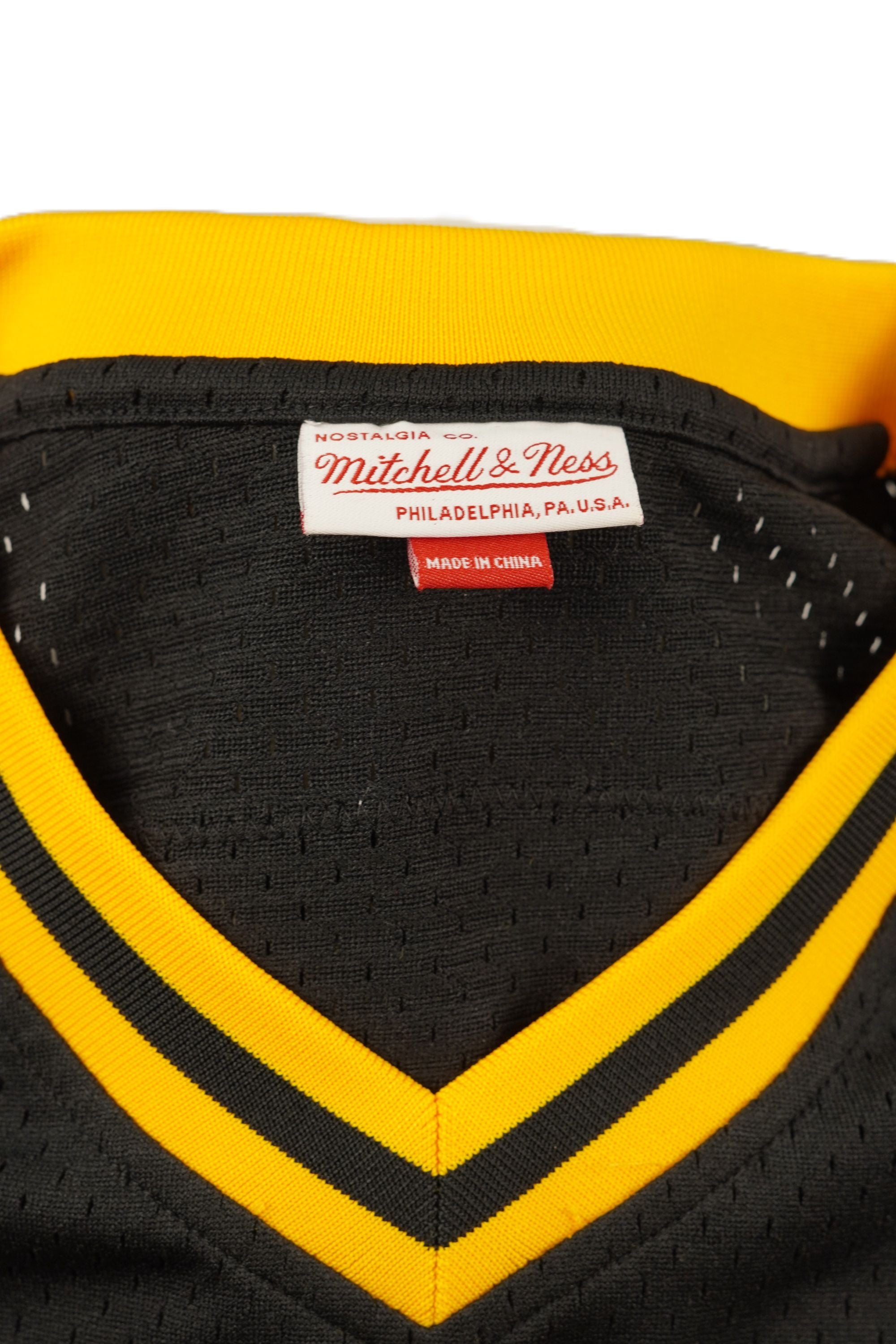 Primo piano dell'interno del collo con l'etichetta ricamata Mitchell & Ness Nostalgia Co. e l'indicazione della taglia M.