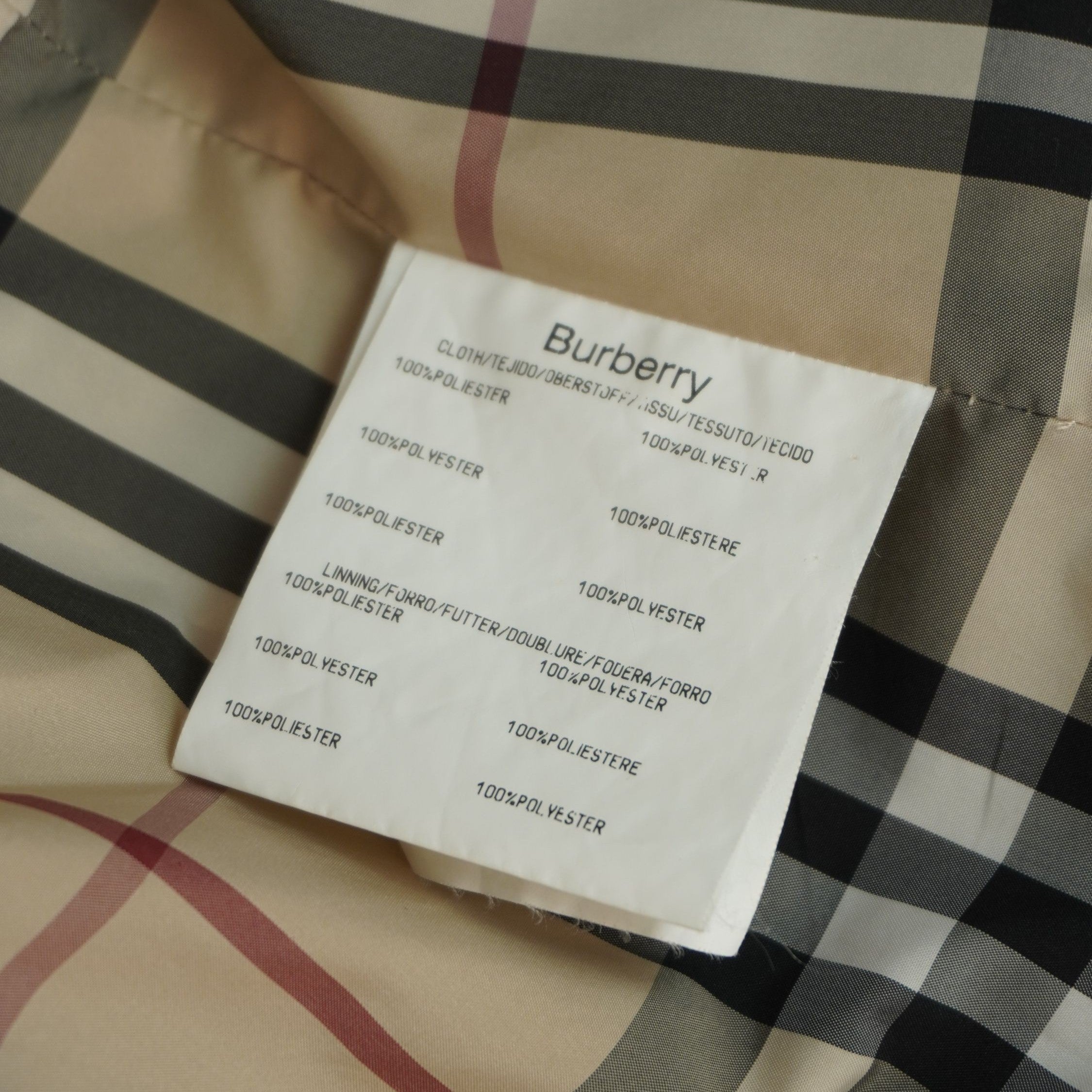 Primo piano dell'etichetta interna bianca in tessuto con le istruzioni per il lavaggio e i materiali di composizione della giacca Burberry.