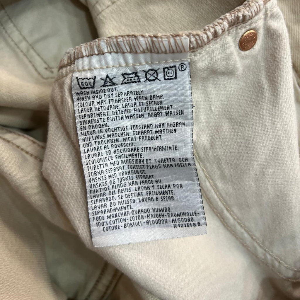 Inquadratura ravvicinata dell'etichetta interna in tessuto stampato con le istruzioni di lavaggio, i codici di produzione e la dicitura Made in Italy.